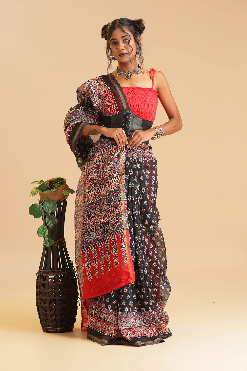 Full-length studio view of a model wearing the black handblock printed Chanderi cotton-silk saree with red print and border, styled with a vibrant red blouse and traditional silver jewelry