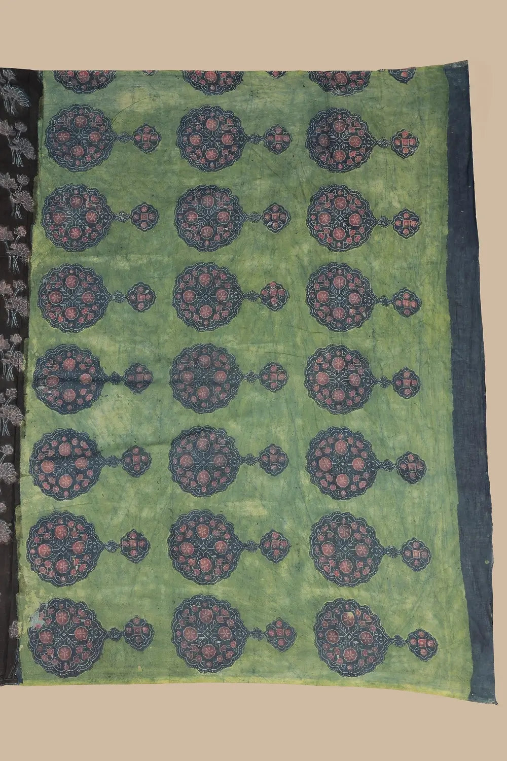 Detail view of the olive green contrasting pallu featuring bold circular medallion motifs in madder red and black