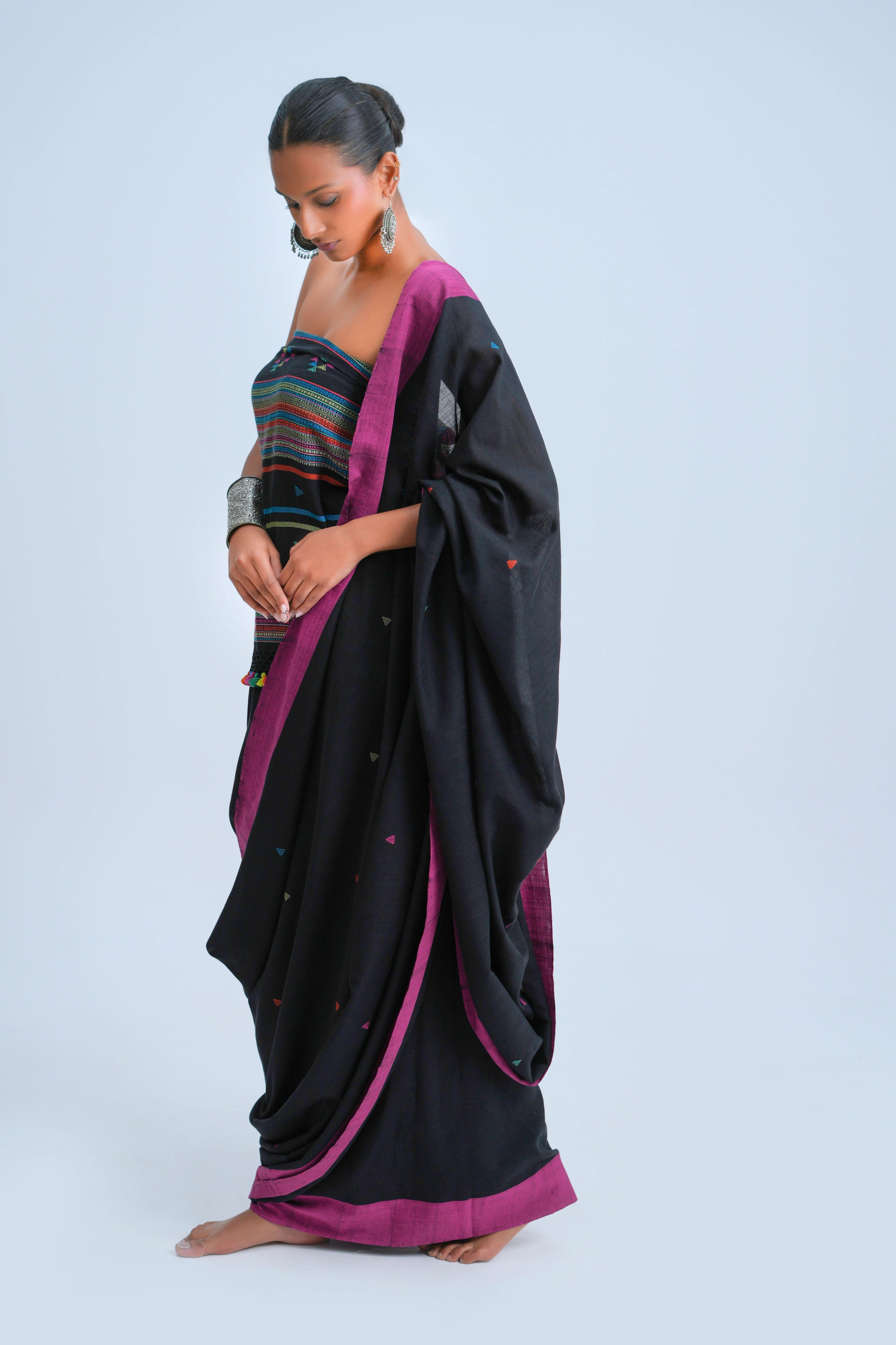 Side-profile view of a model showcasing the graceful fall and magenta border of the black Bhujodi saree