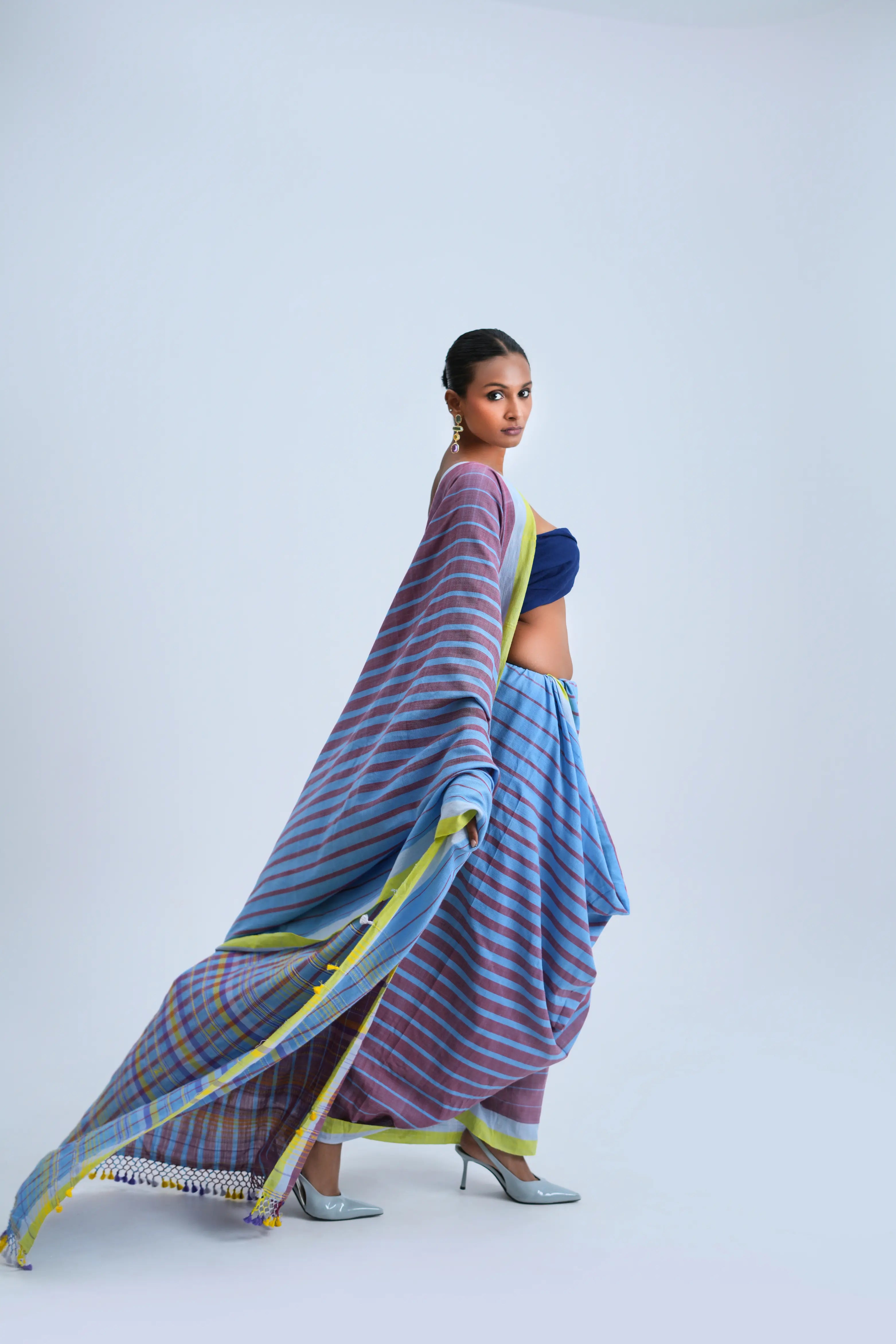 Side-profile view of a model highlighting the graceful flow, drape, and length of the striped Bhujodi saree