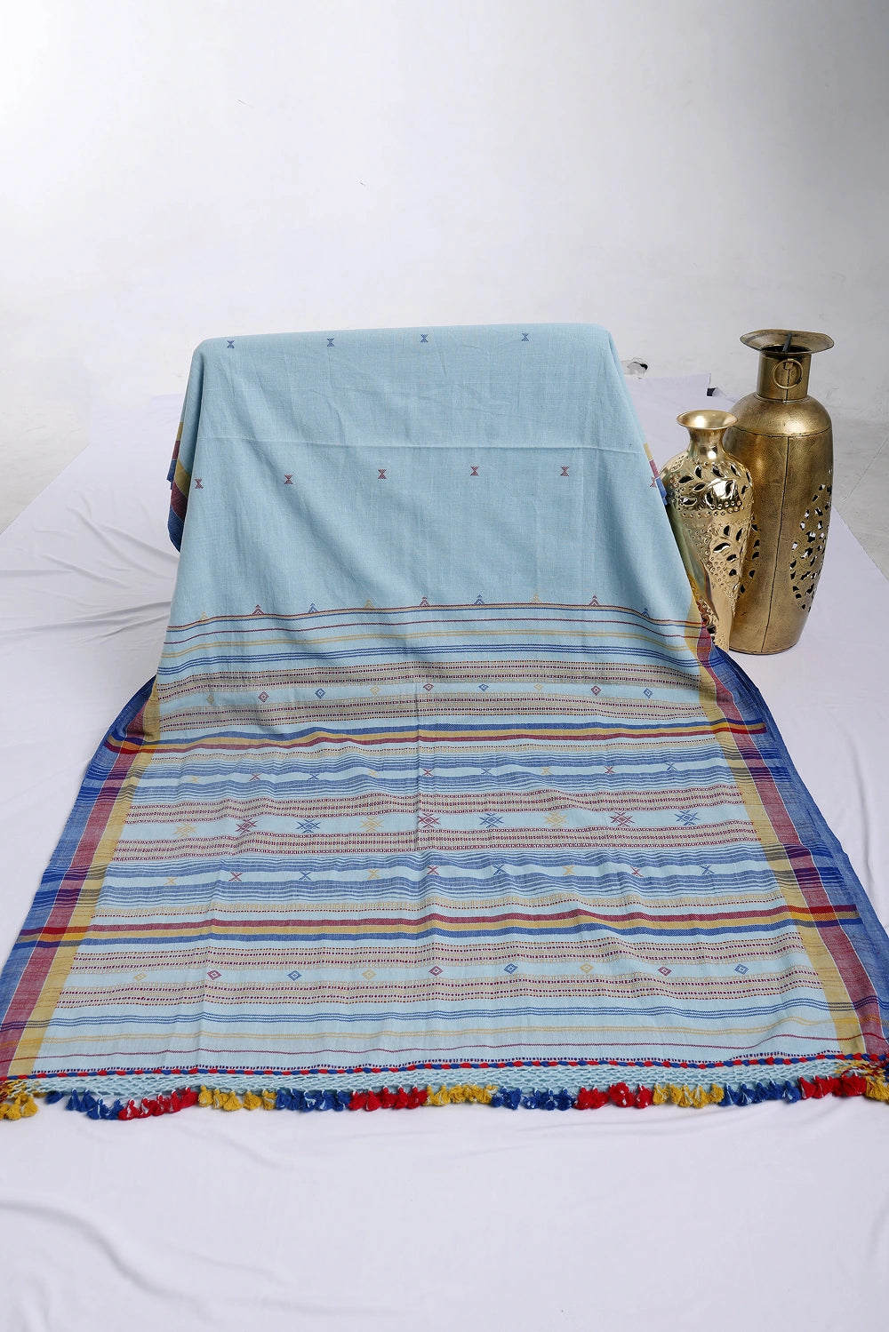 Folded product display showcasing the rich horizontal stripe texture, color variation, and decorative brass vase prop