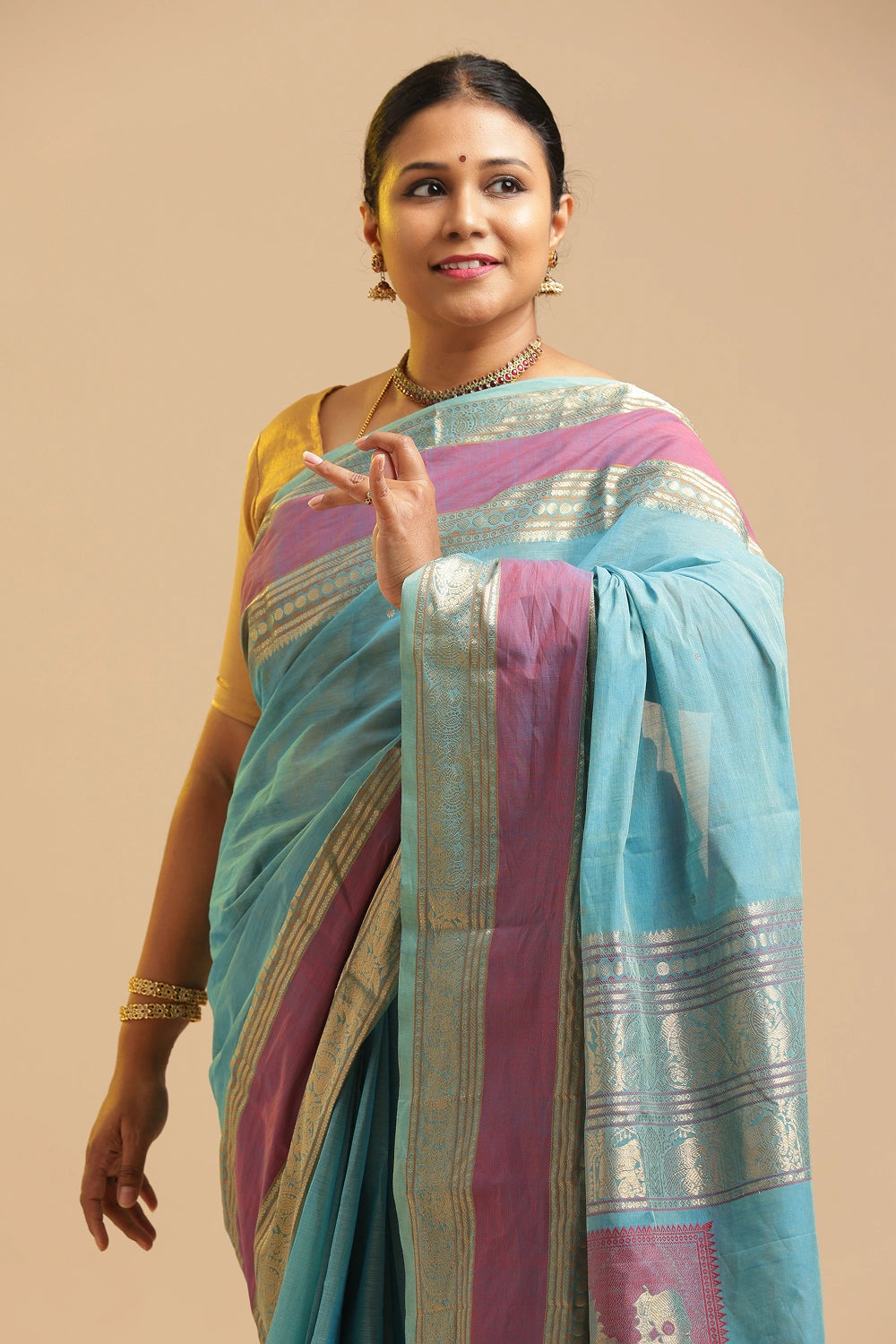 Model posing gracefully in the pastel blue Kanchipuram cotton saree against a neutral studio background