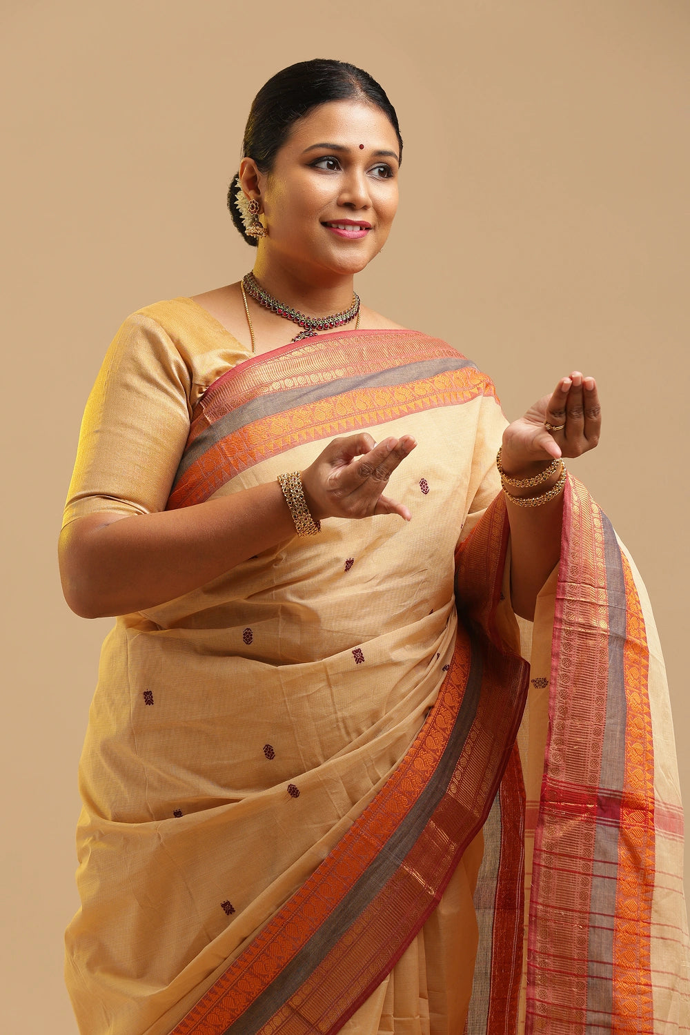 Model gracefully posing in the soft cream cotton saree against a neutral studio backdrop