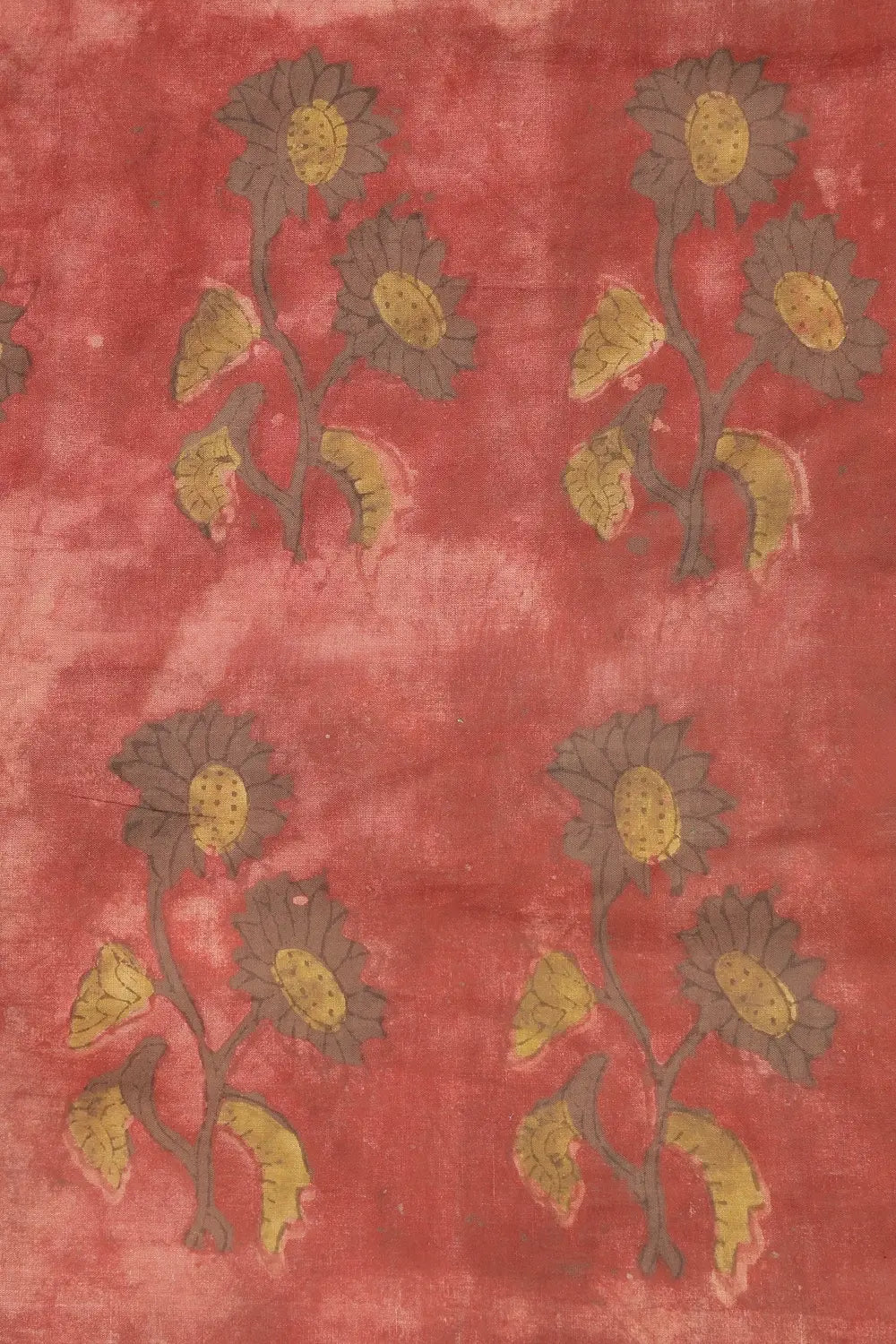 Close-up view of the red dyed cotton fabric highlighting the yellow and brown hand-block printed floral motifs