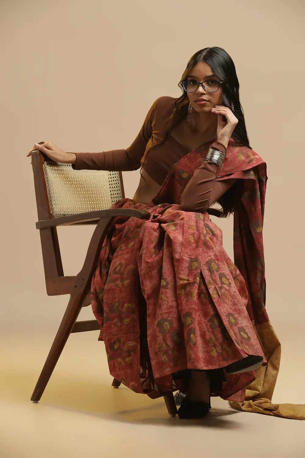 Model posing in the crimson earth cotton saree against a neutral studio backdrop