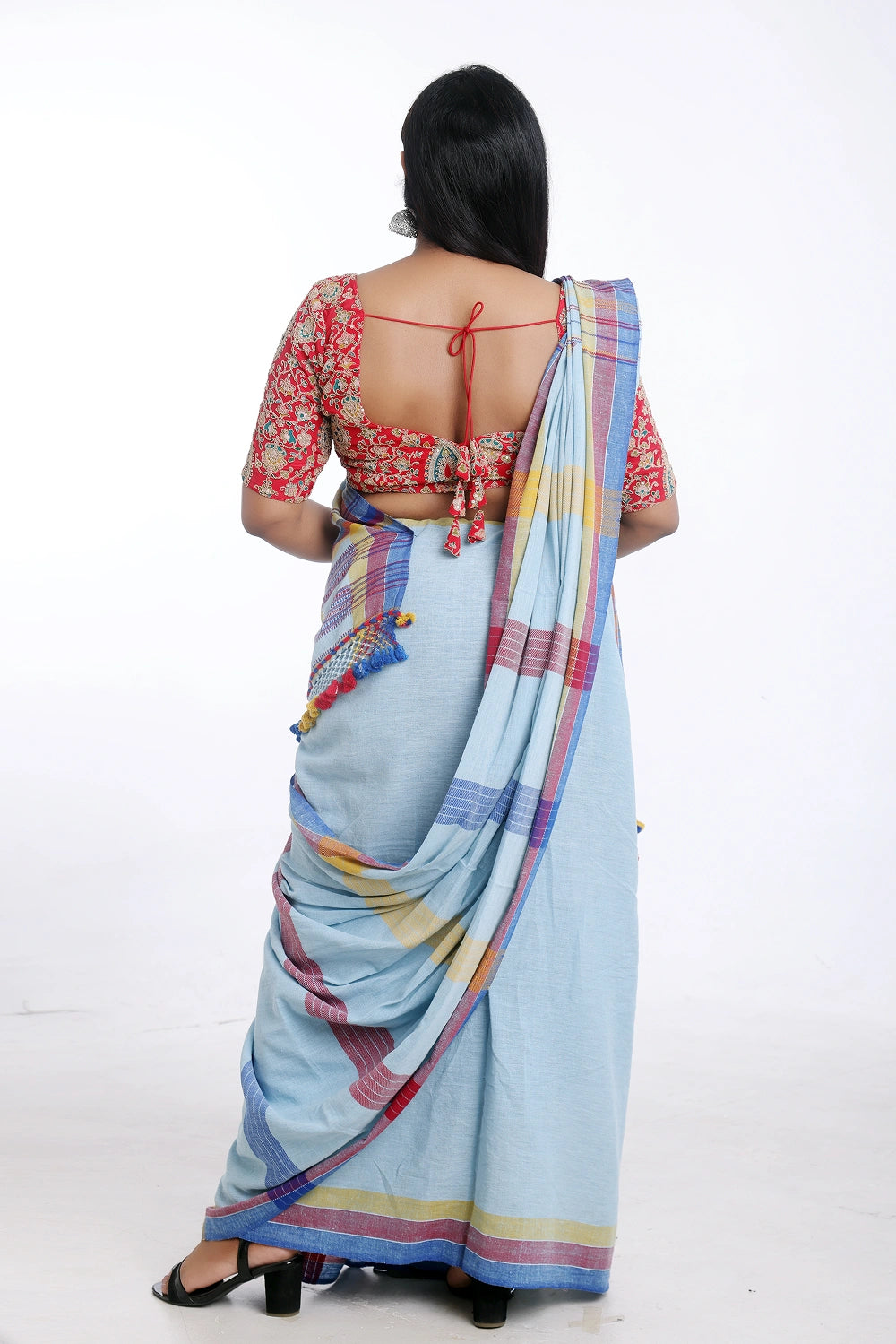 Rear full-length view of a model displaying the back silhouette and draped stripes of the light blue Bhujodi saree