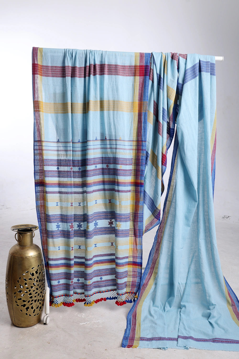 Folded product display showcasing the rich horizontal stripe texture, color variation, and decorative brass vase prop