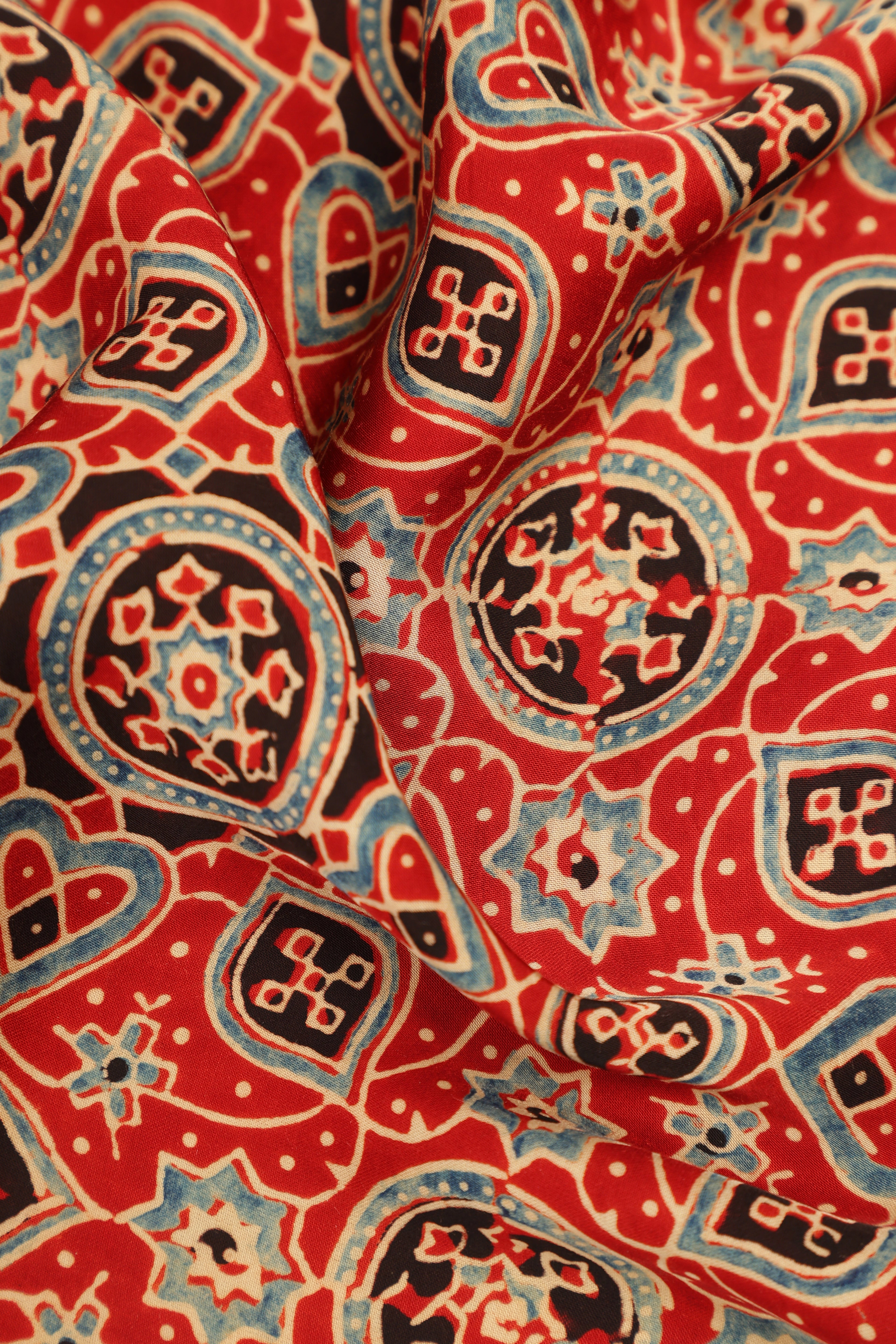 Close-up view of the folded modal silk fabric highlighting the vibrant organic color depth and traditional Ajrakh block-printed motifs