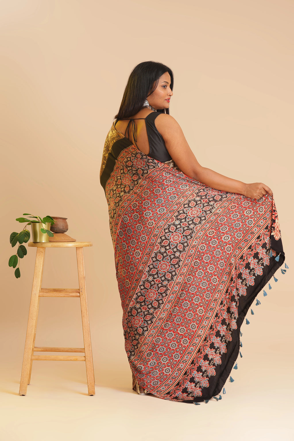 Studio standing side angle view showcasing the rich rust red and black pallu details of the handcrafted Ajrakh sare