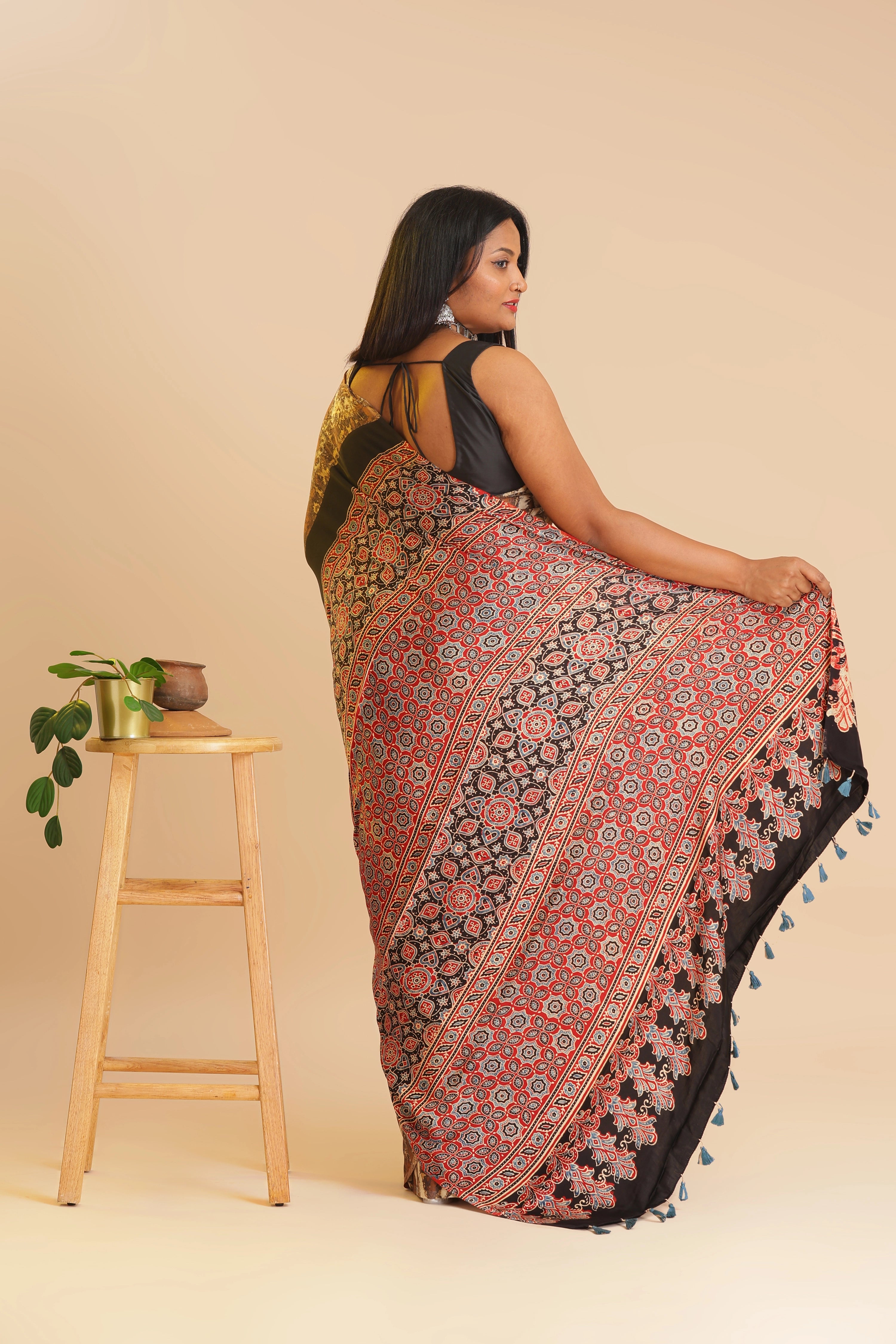 Studio standing side angle view showcasing the rich rust red and black pallu details of the handcrafted Ajrakh sare