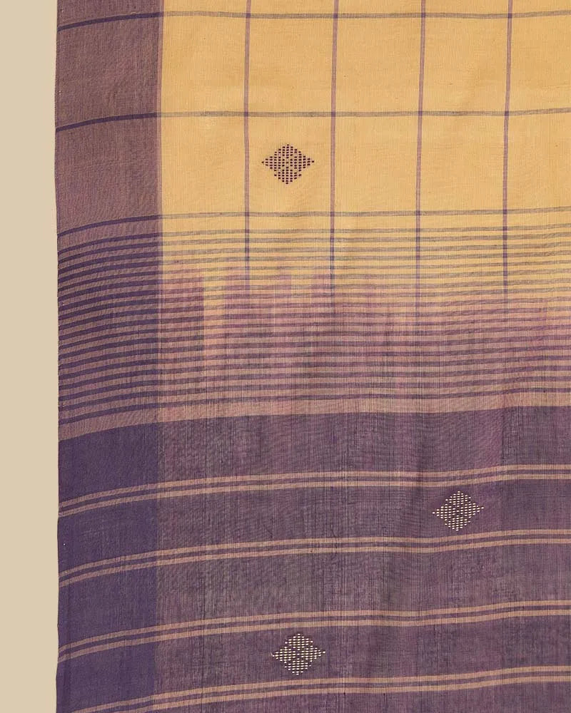 Close-up fabric shot highlighting the golden ochre body with checked pattern, buti motifs, and royal purple border