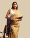 Full-length studio view of a model wearing the golden ochre Kasaragod cotton saree with a checked body and contrasting royal purple pallu, paired with a white blouse