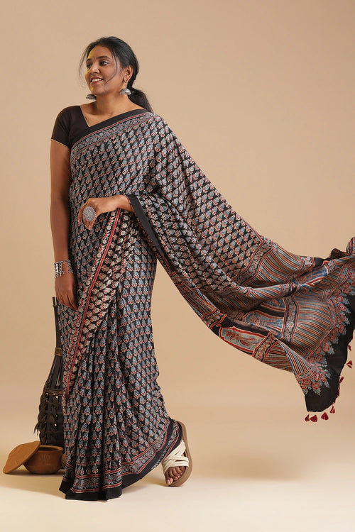 Studio motion view capturing the model sweeping the patterned pallu outward, highlighting the rich dark textile flow and handcrafted Kutch details