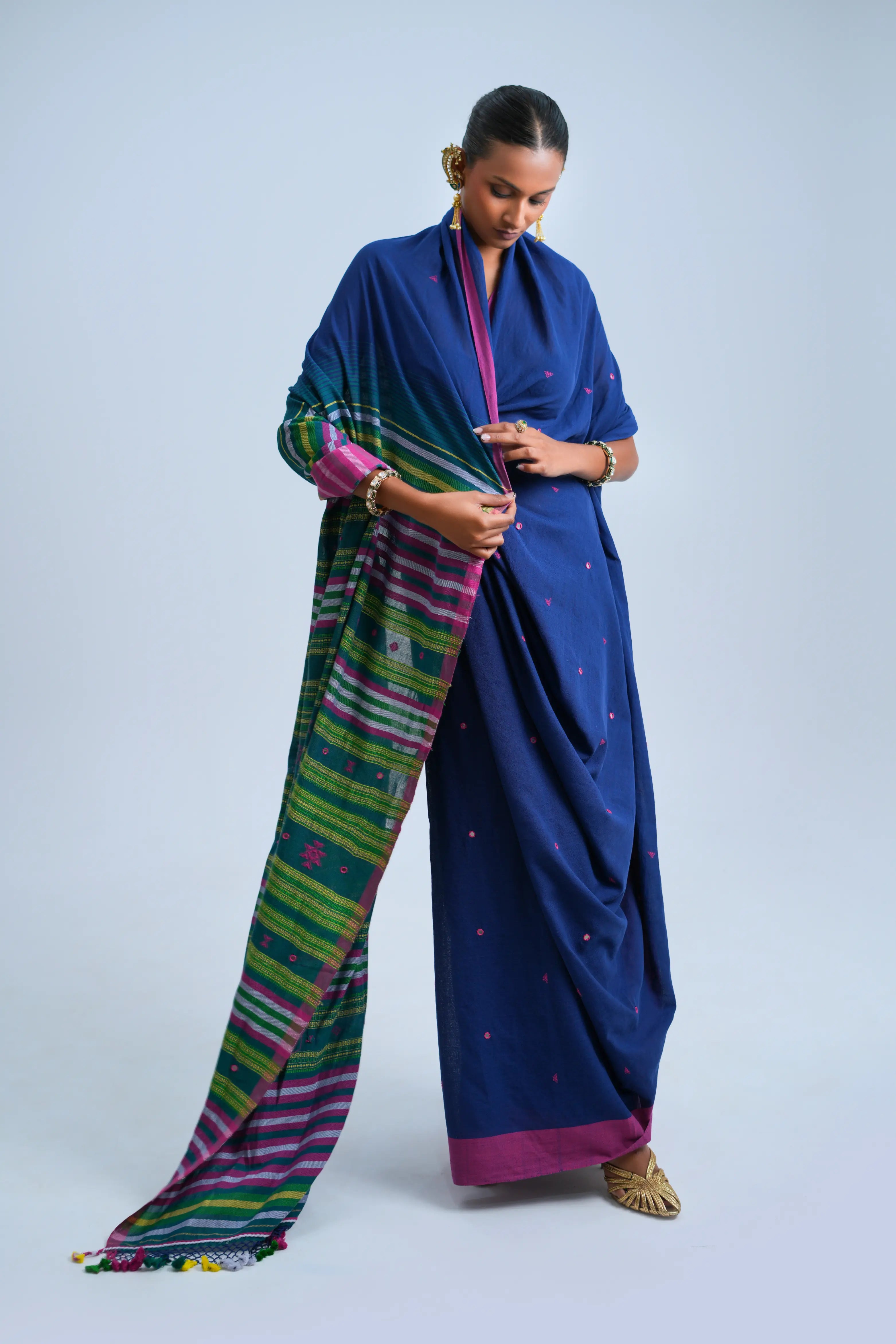 Full-length view of a model wearing the deep indigo blue organic Kala cotton Bhujodi saree with fuchsia-pink borders and a multicolour striped pallu