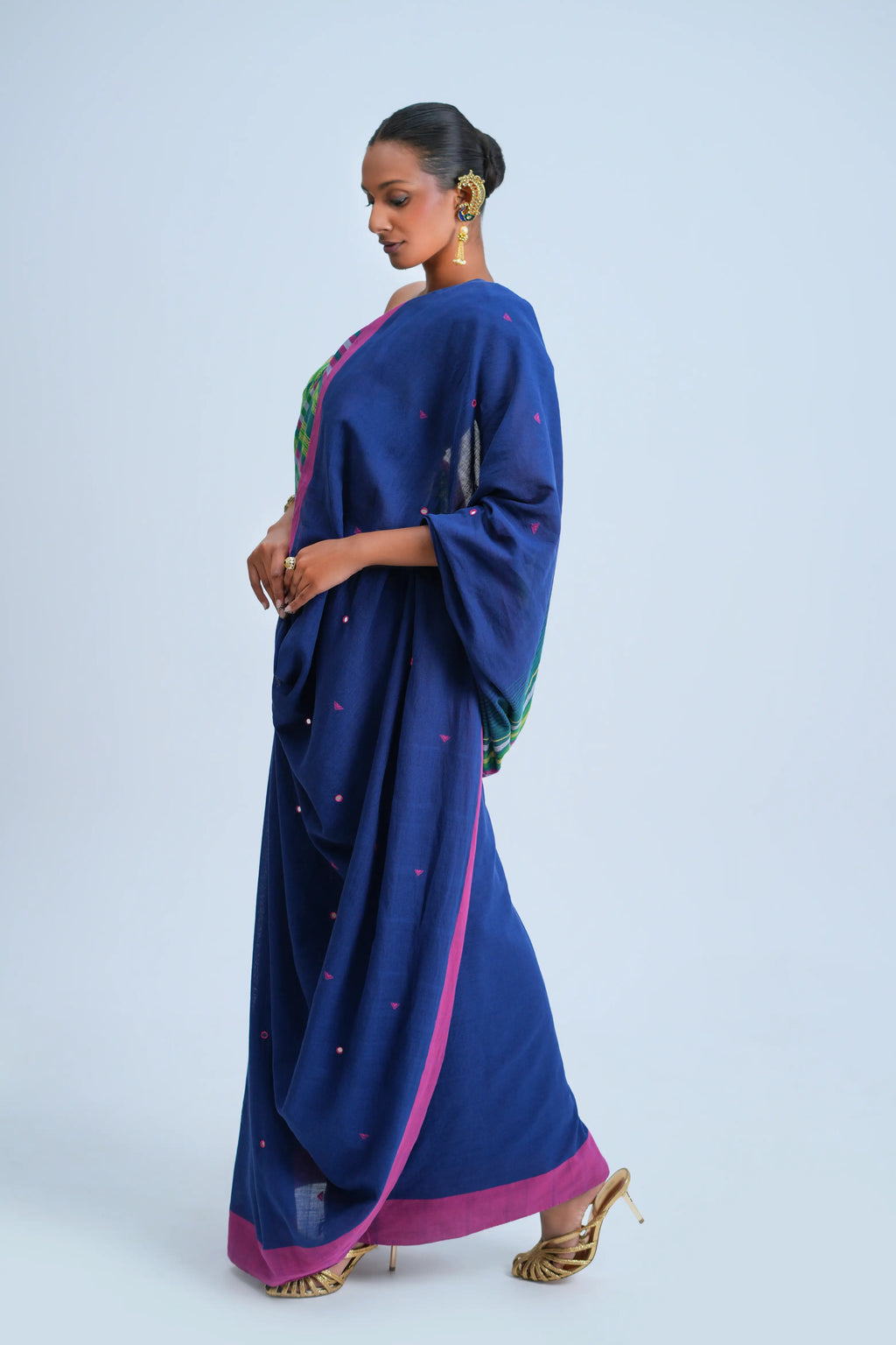 Side-profile view of a model showcasing the graceful fall and vibrant pink border alignment of the indigo Bhujodi saree
