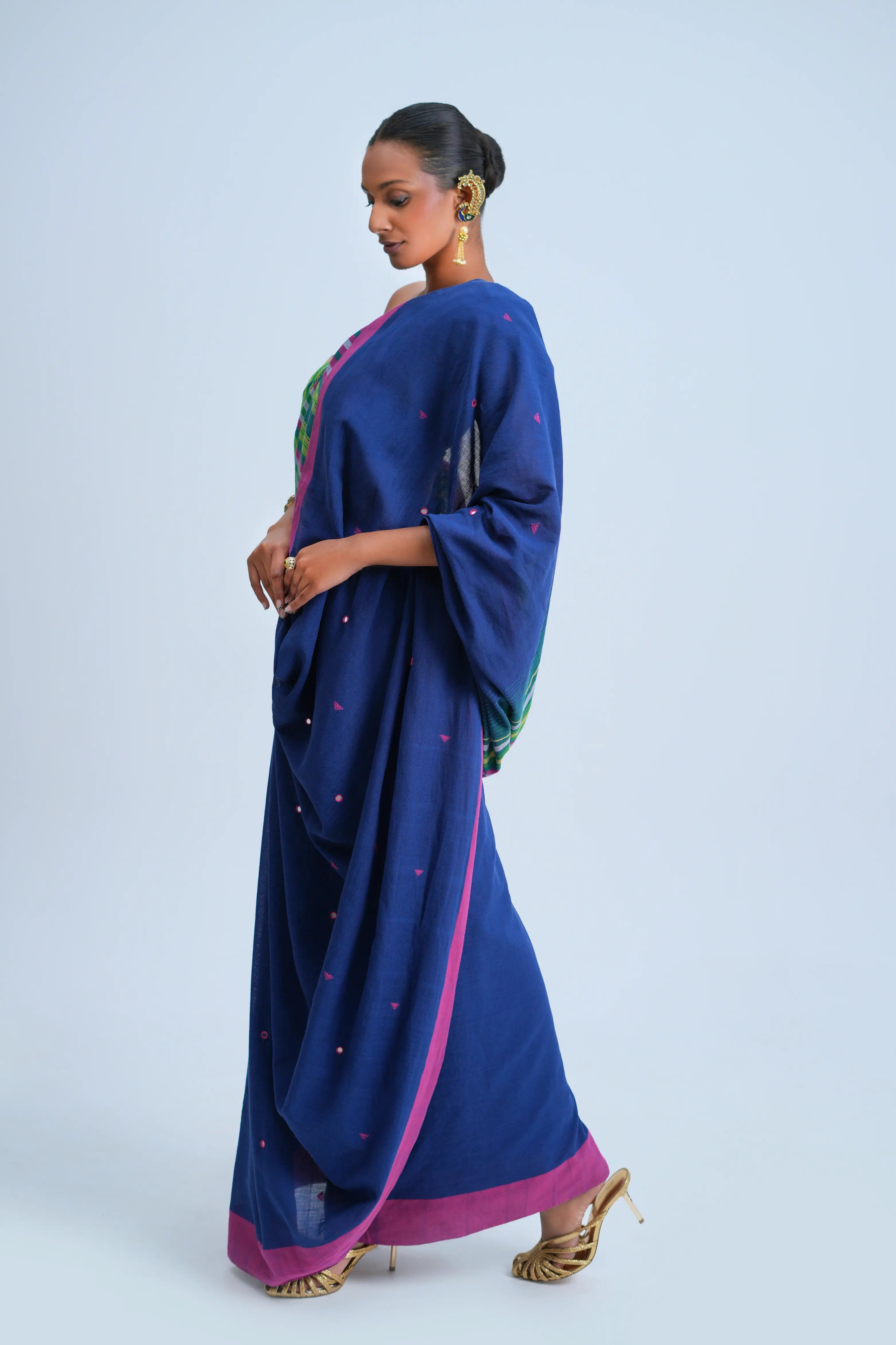 Side-profile view of a model showcasing the graceful fall and vibrant pink border alignment of the indigo Bhujodi saree