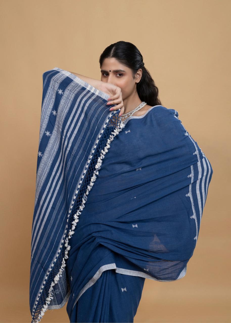 Close-up view of the bold striped pallu, traditional star motifs, and artisan ivory tassel fringe held over the model's arm