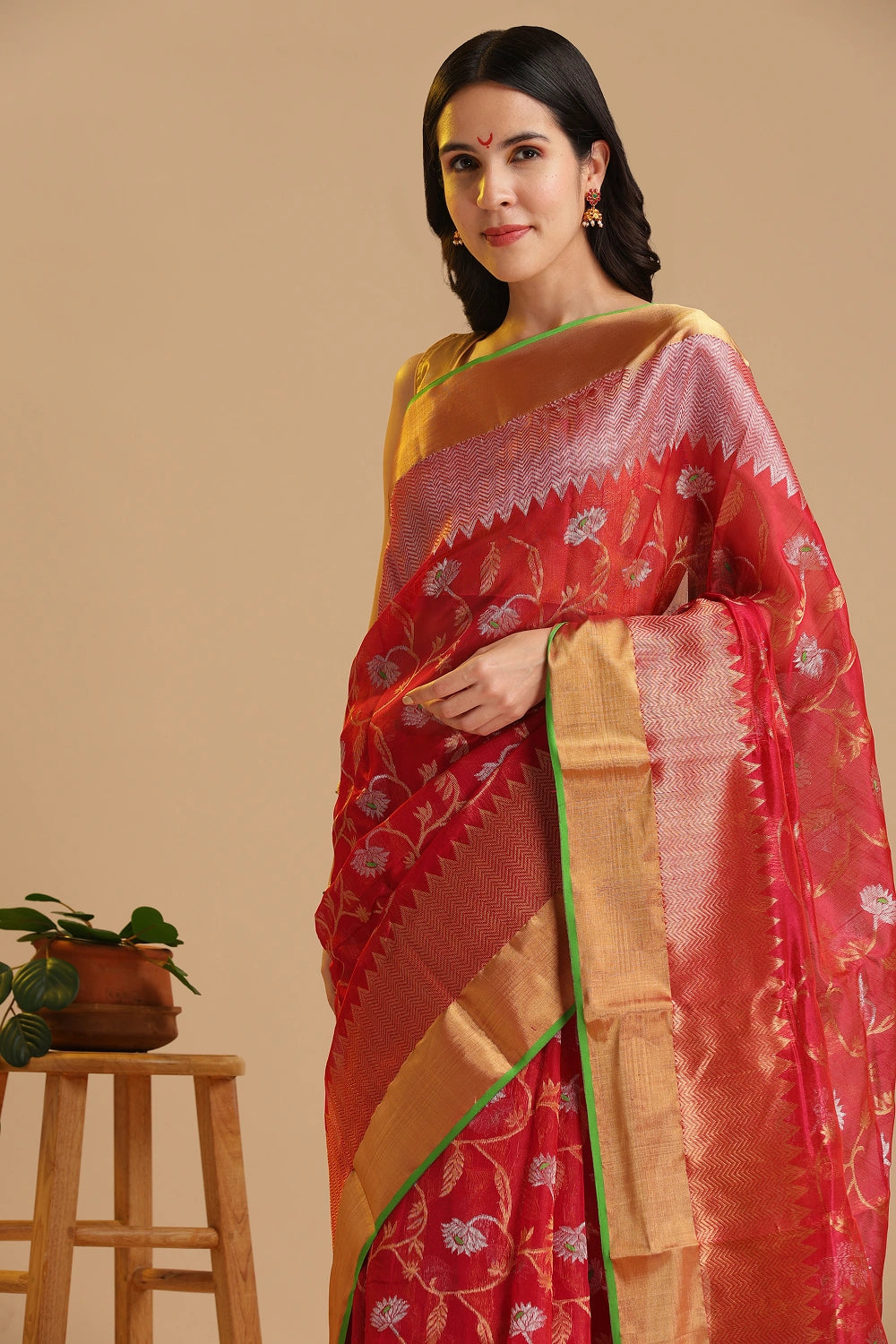 Studio standing angle view showcasing the graceful drape and vibrant red and gold color palette of the Chanderi pattu silk saree