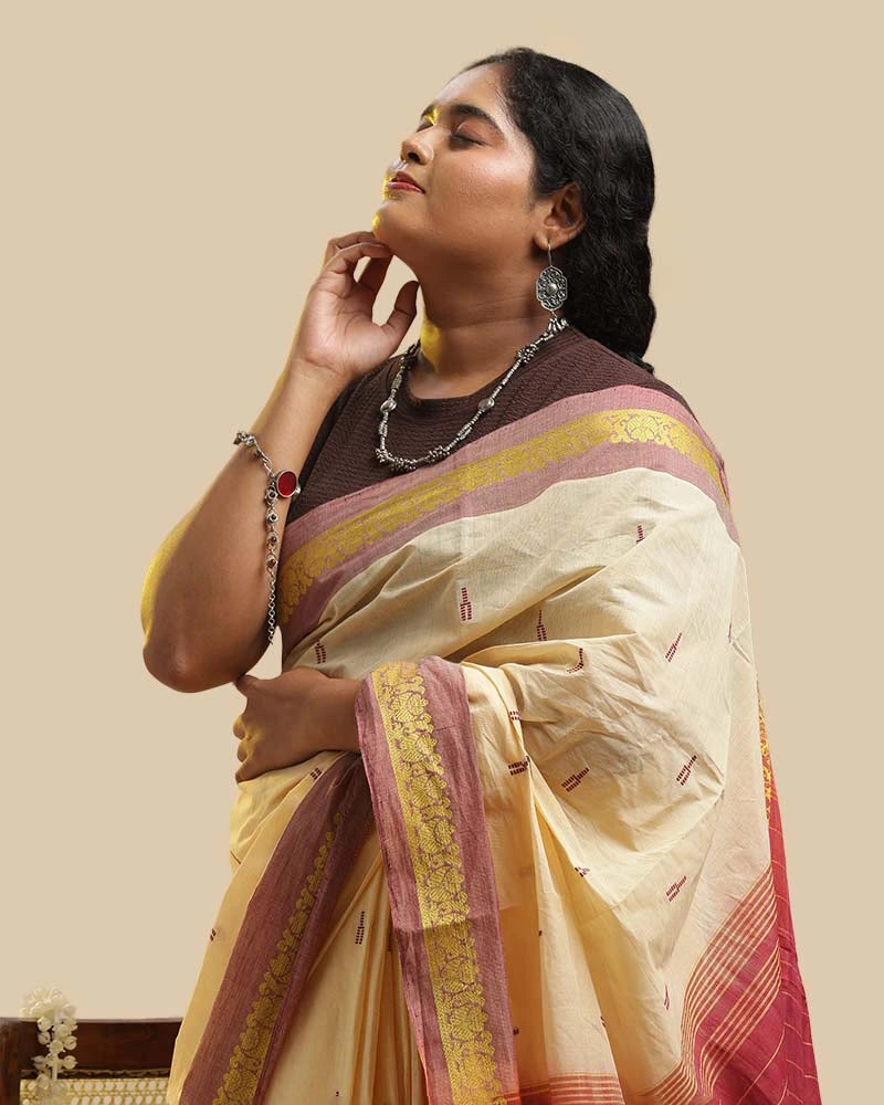 Side-profile studio view highlighting the graceful drape, mustard border, and delicate shoulder pleats of the Kasaragod handloom saree