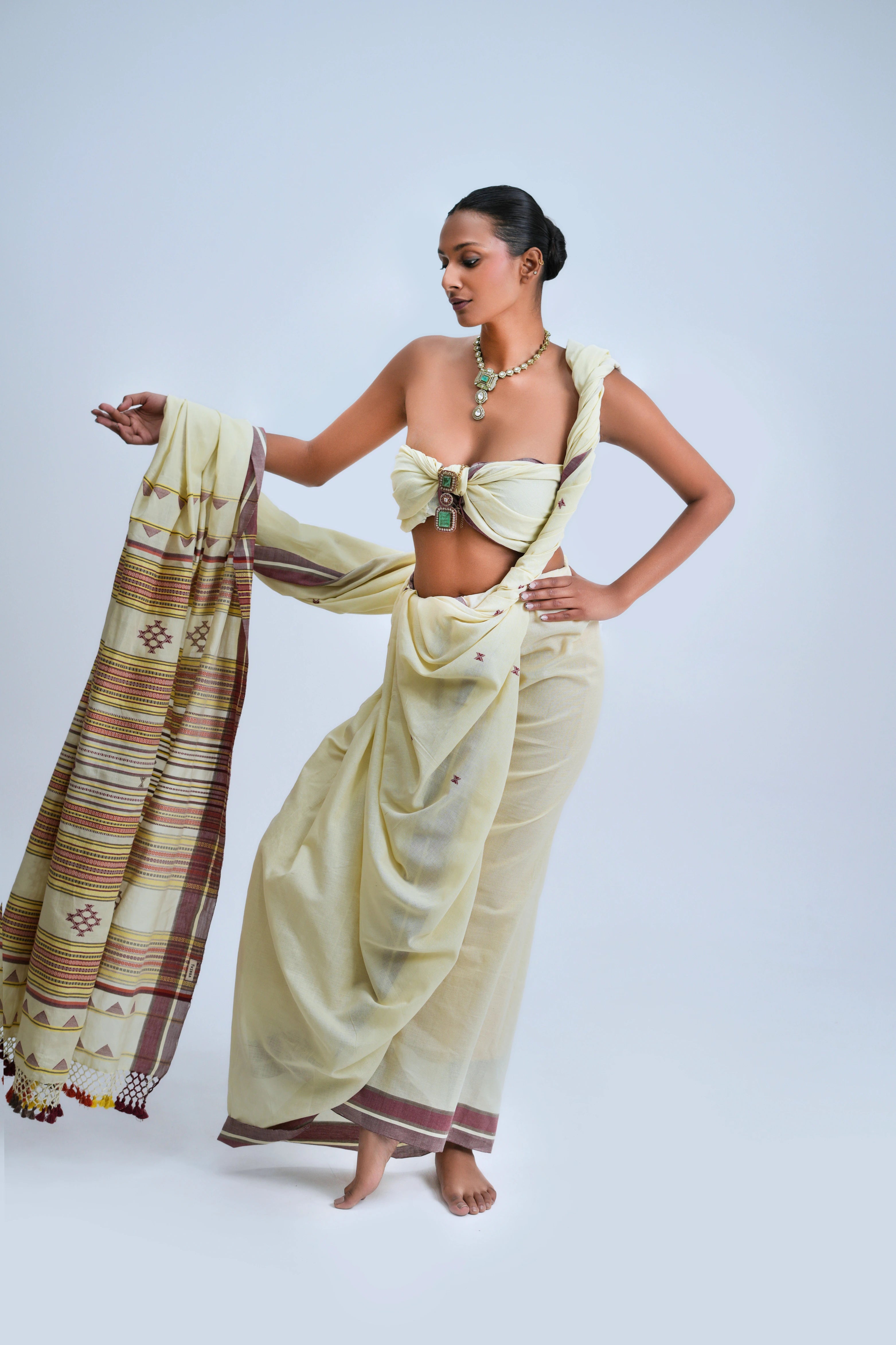 Full-length front view of a model wearing the luminous ivory cream organic Kala cotton Bhujodi saree featuring deep maroon borders and a multicolour striped pallu
