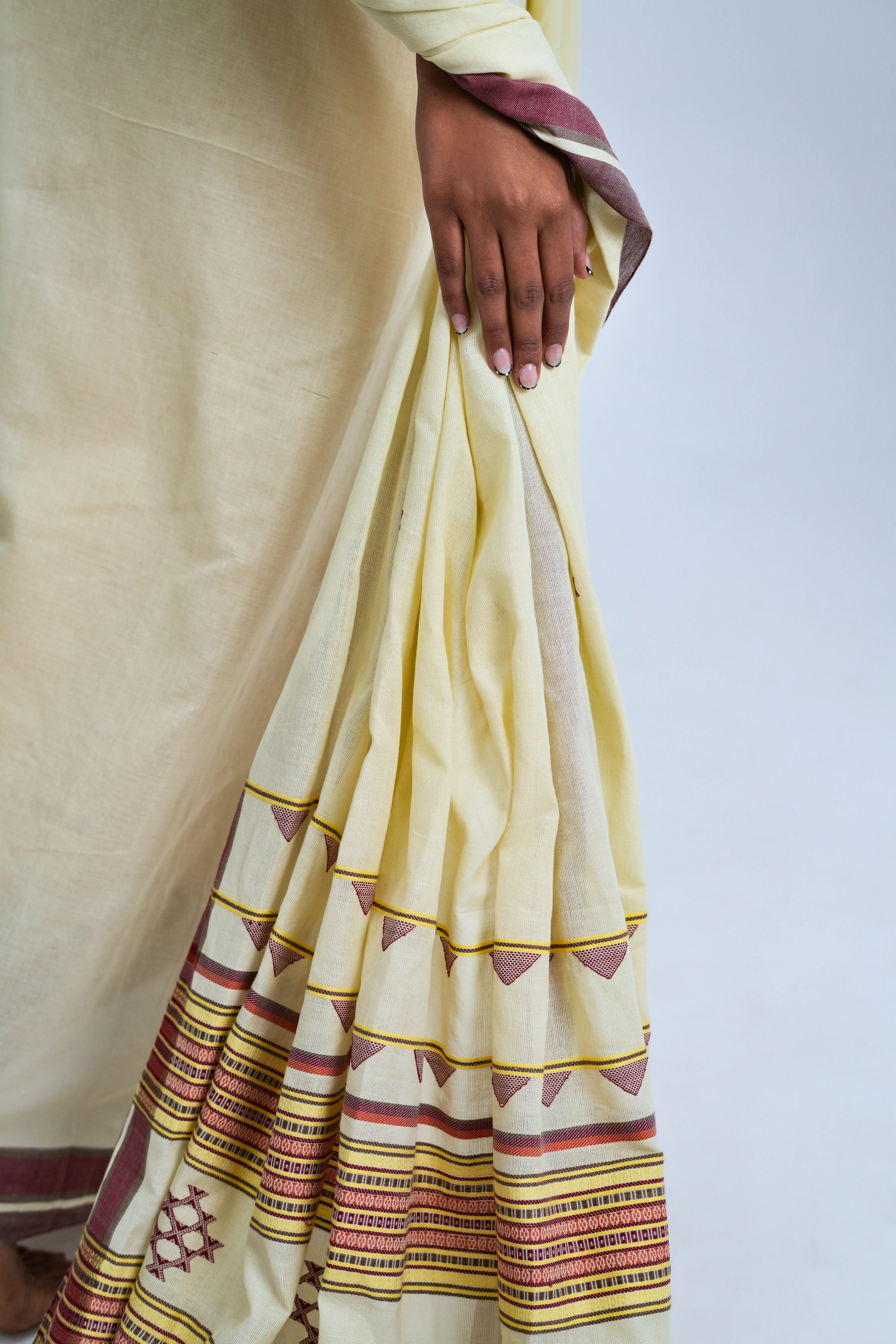 Close-up view of the neatly stacked pleats highlighting the deep maroon border with yellow pinlines and ivory fabric texture