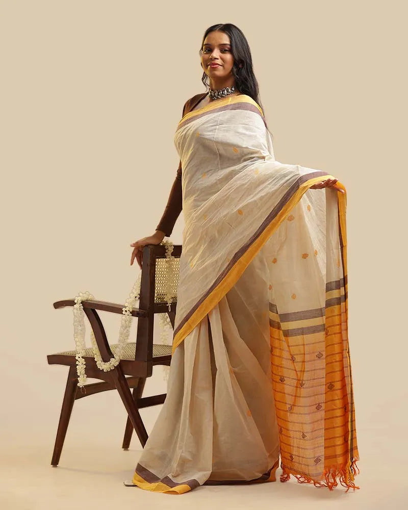Full-length studio view of a model posed with a wooden chair, highlighting the complete silhouette, pleats, and contrasting mustard pallu