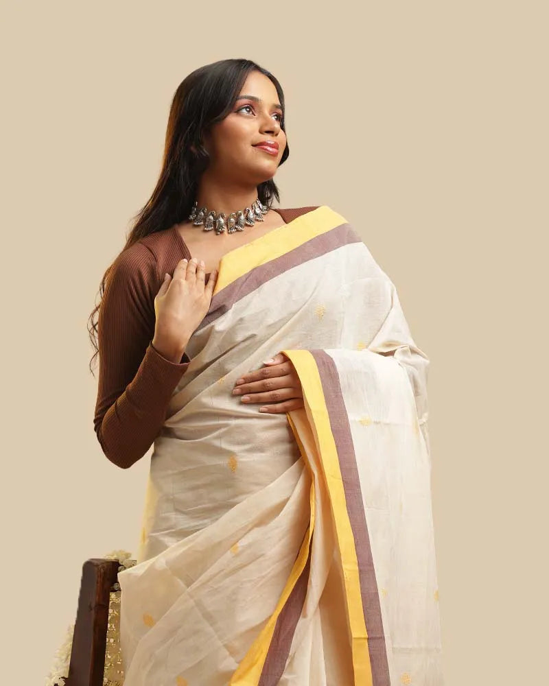 Standing studio view showcasing the soft ivory body, mustard border with fine grey accents, and overall drape of the Kasaragod handloom saree
