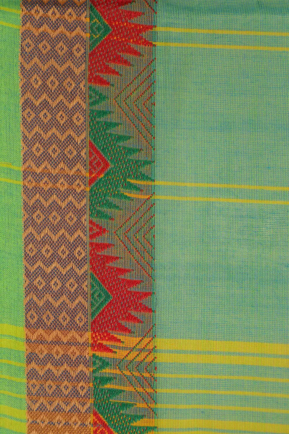 Close-up view of the contrasting red and gold patterned border on the light green cotton fabric