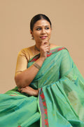 Light green Kanchi powerloom cotton saree featuring delicate self-motifs and a contrasting red and gold border displayed by a model