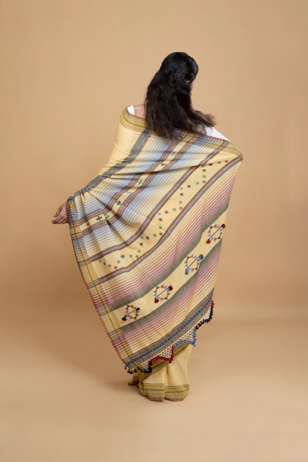 Rear full-length view of a model displaying the graceful fall, draped pleats, and finished pallu border of the butter yellow Bhujodi saree