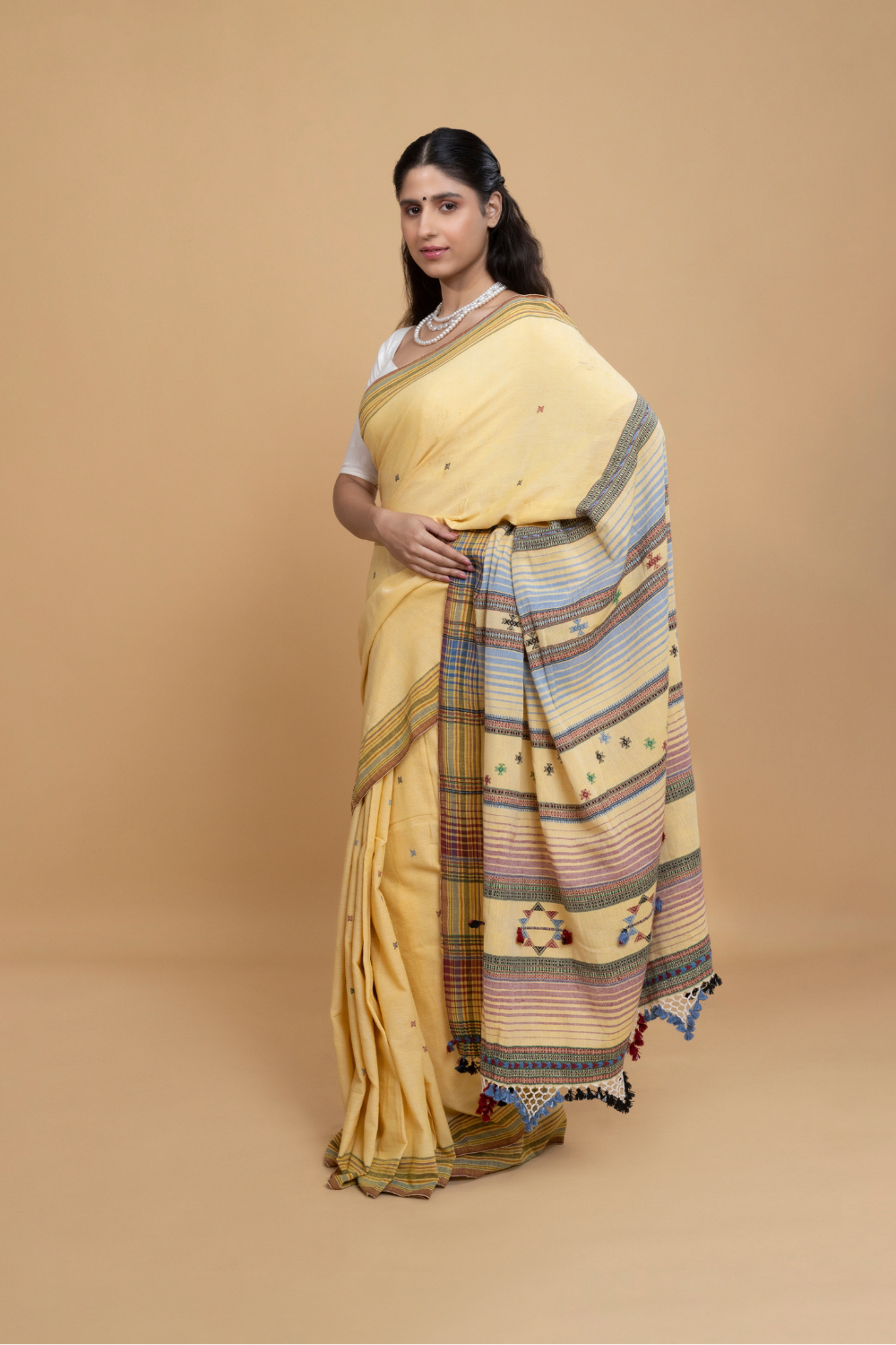 Standing front view showcasing the soft butter yellow body, subtle buti motifs, and elegant pleat alignment of the Bhujodi saree