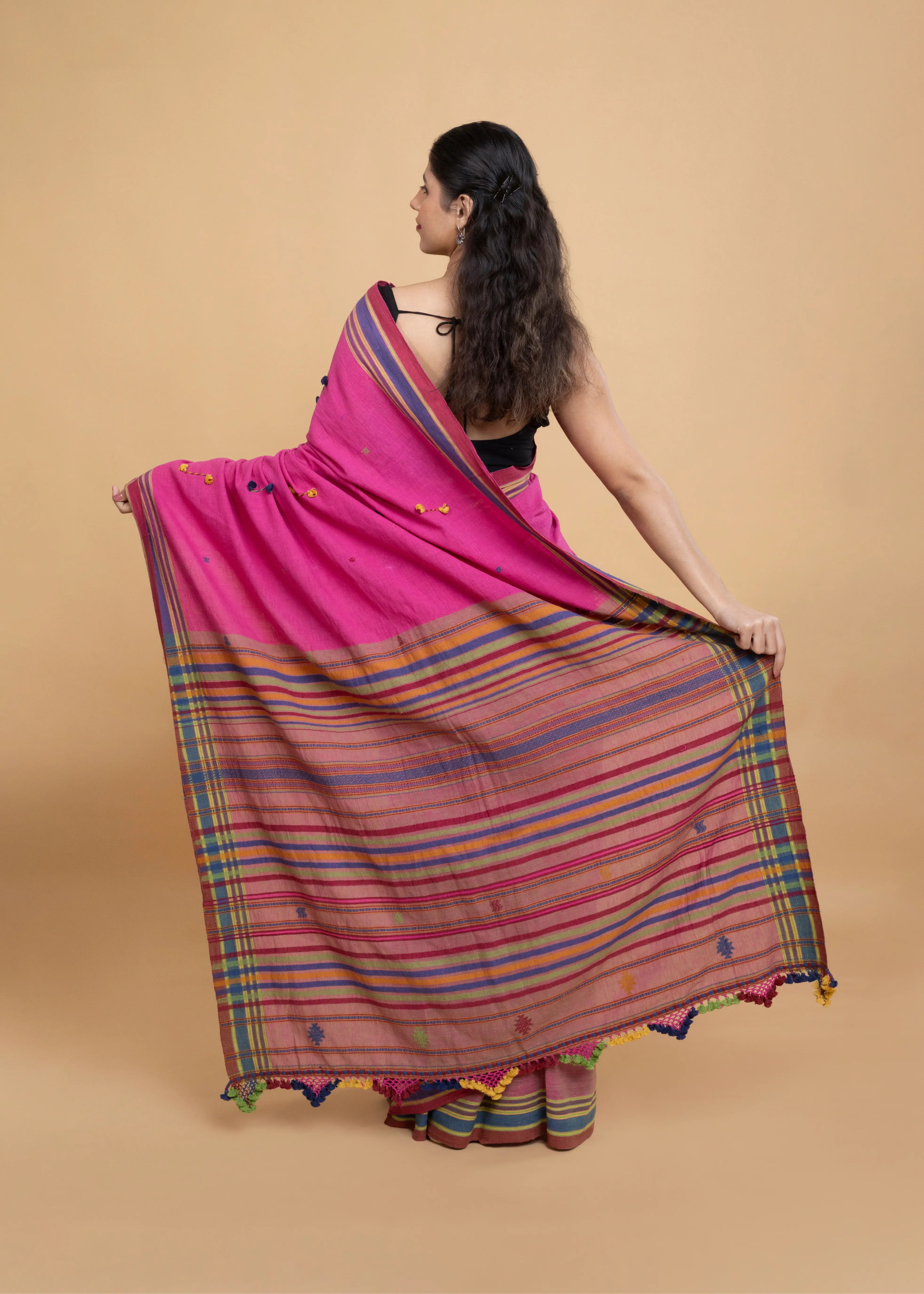 Rear view of a model displaying the detailed plaid pattern and pom-pom fringe along the pallu edge