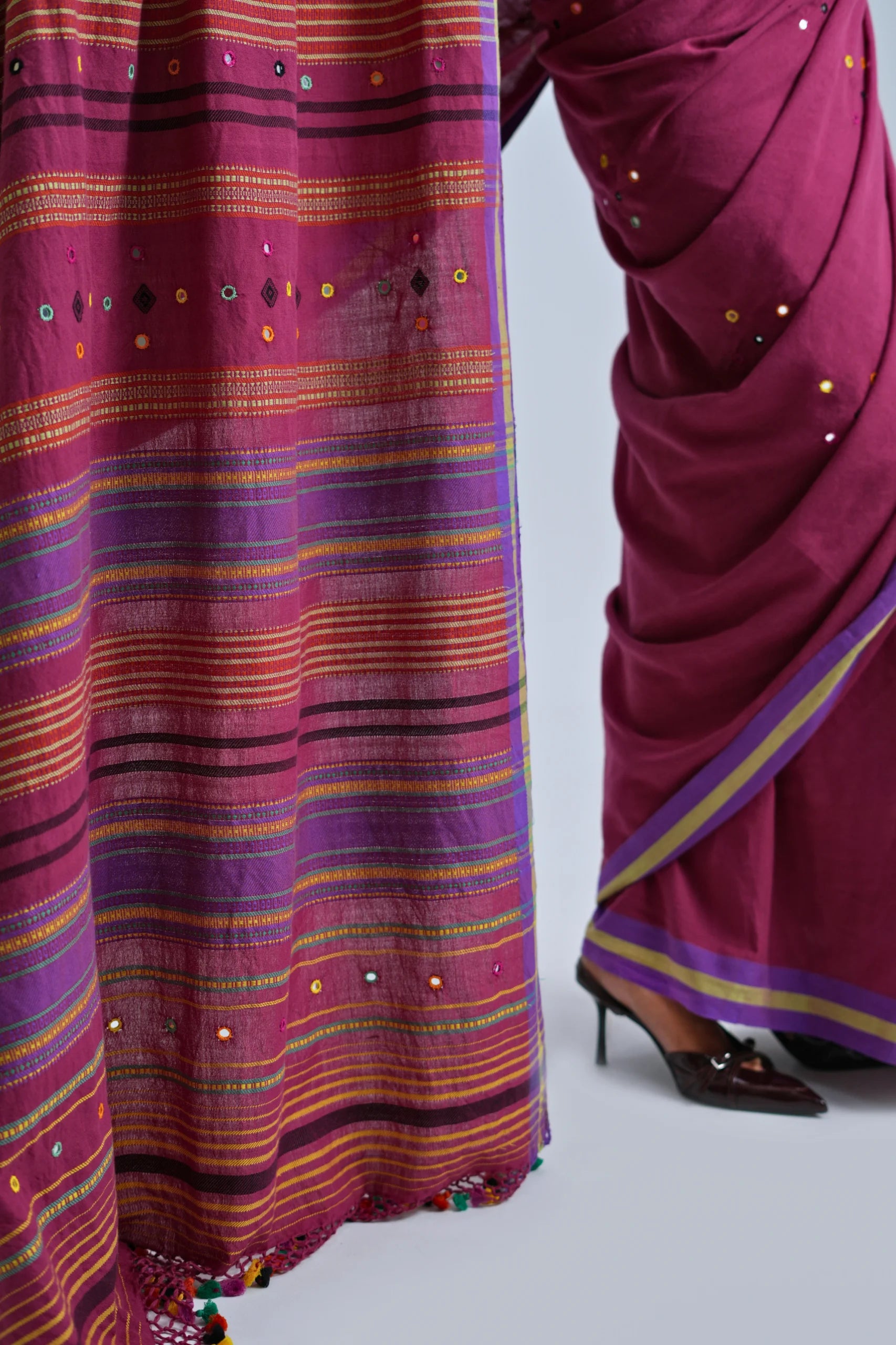Detailed close-up of the multi-coloured horizontal stripe pallu, geometric woven bands, and multicolour pom-pom fringe