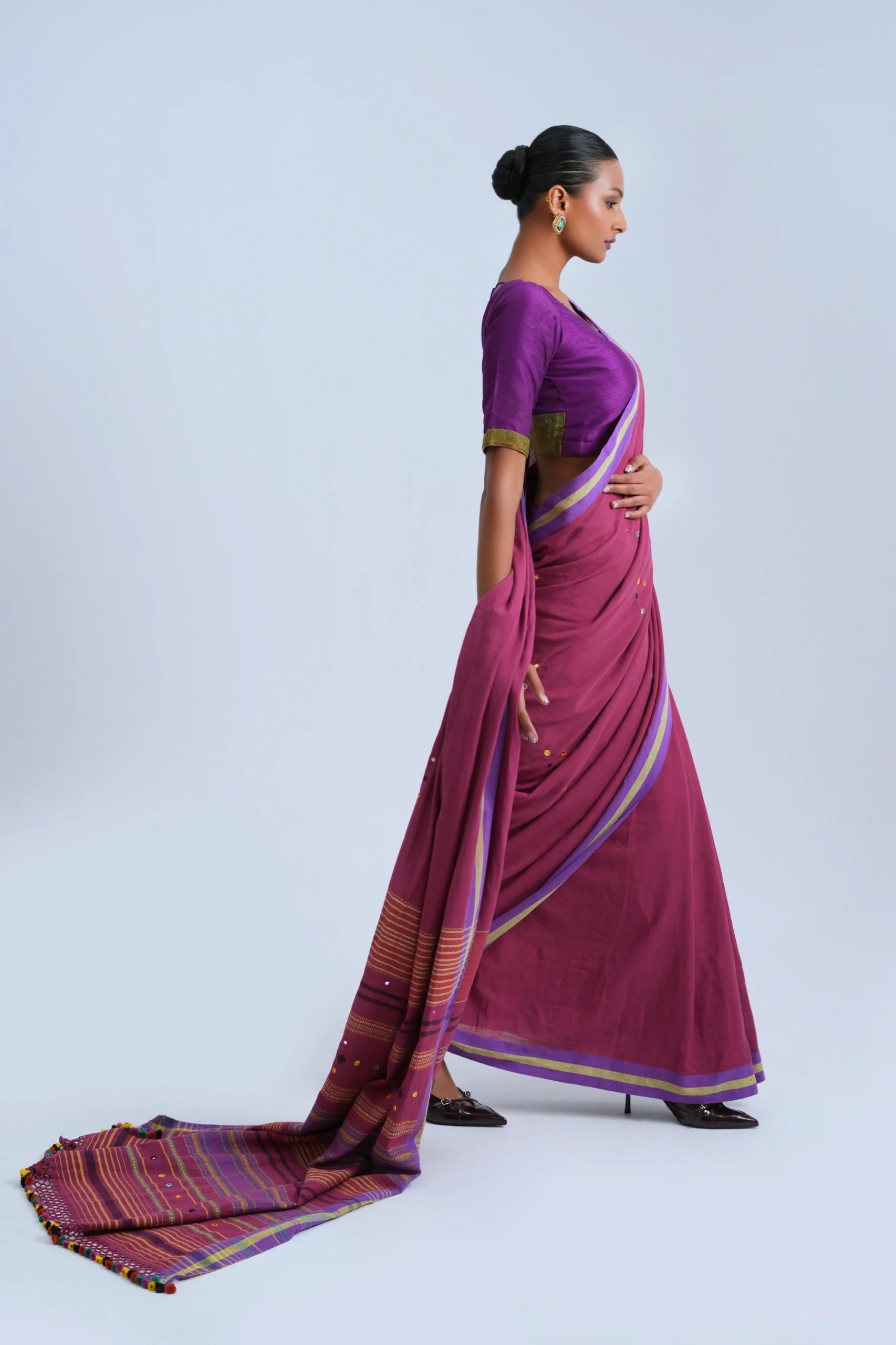 Side-profile studio view showing the fluid fall and length of the magenta Bhujodi saree with the pallu extended