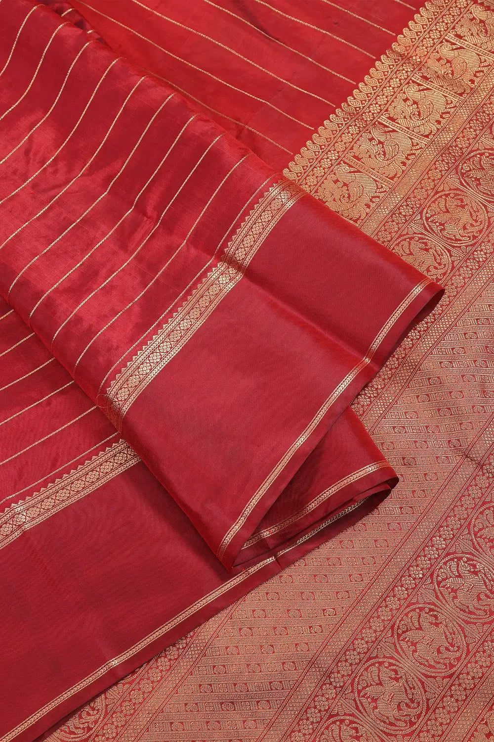 Detailed view of the woven gold zari folds and border detailing of the maroon silk saree