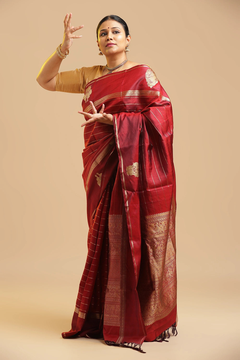Model gracefully posing in the deep maroon Kanchipuram silk saree showcasing its rich traditional drape
