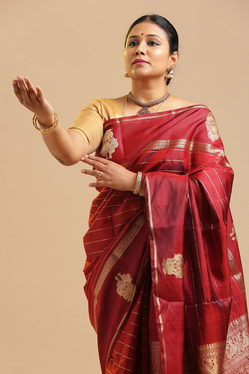 
Maroon Veldhari Kanchipuram handloom silk saree featuring traditional elephant motifs and real gold zari displayed by a model