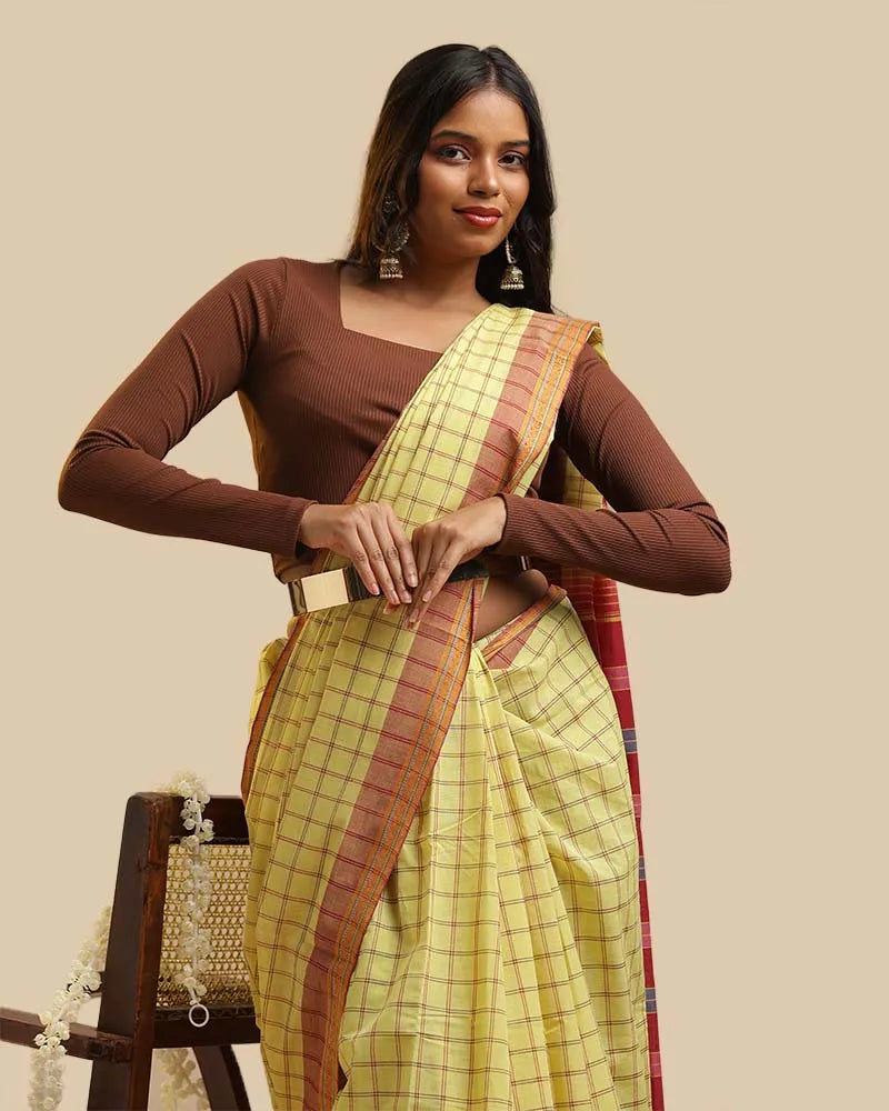 Close-up upper body view showcasing the gentle meadow yellow checked weave, warm rust border, and brown blouse pairing