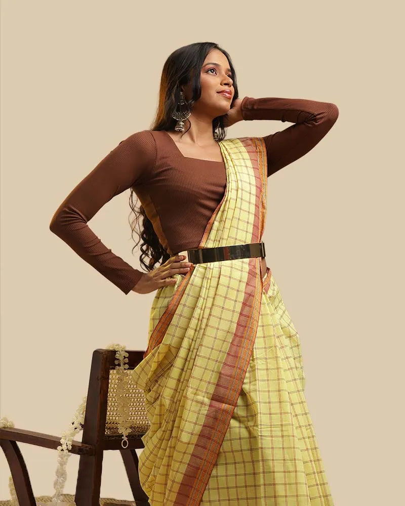 Standing studio view showcasing the belted silhouette, warm rust border, and graceful drape of the meadow yellow Kasaragod handloom saree