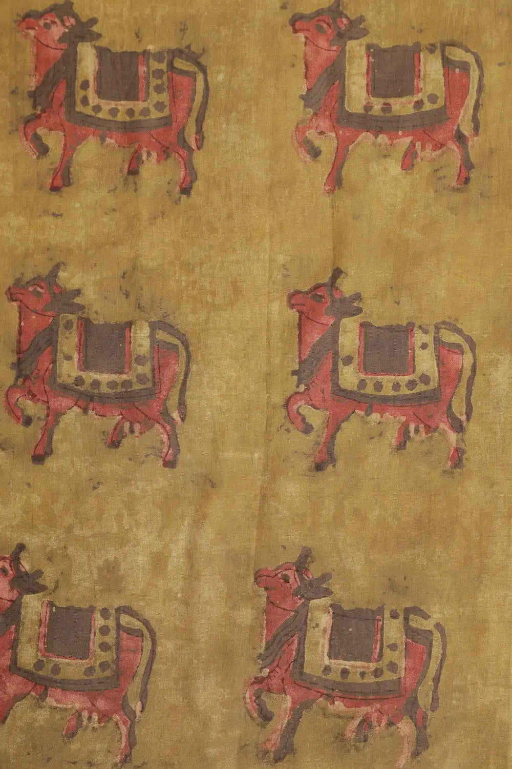 Close-up view of the mustard yellow cotton fabric highlighting the hand-block printed cow motifs created using traditional Bagru techniques