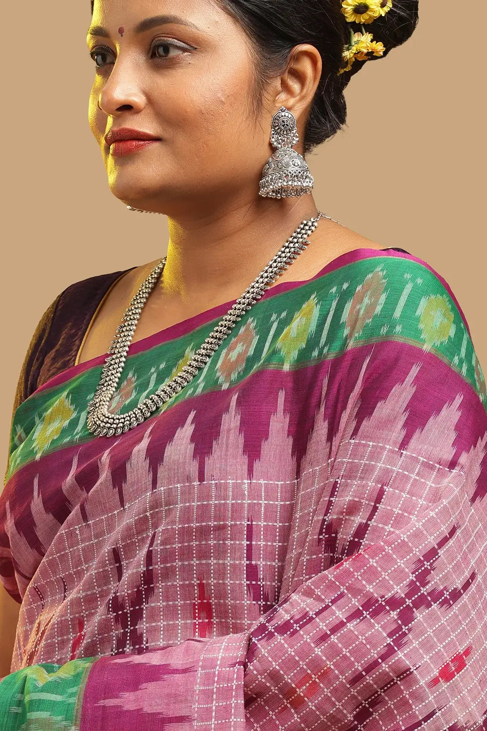 Close-up profile view of the model wearing traditional silver jhumkas and the pink cotton saree