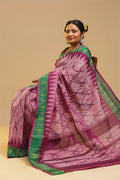 Bright pink and green Muthyampet check cotton saree featuring single ikat patterns and temple design panel displayed by a seated model