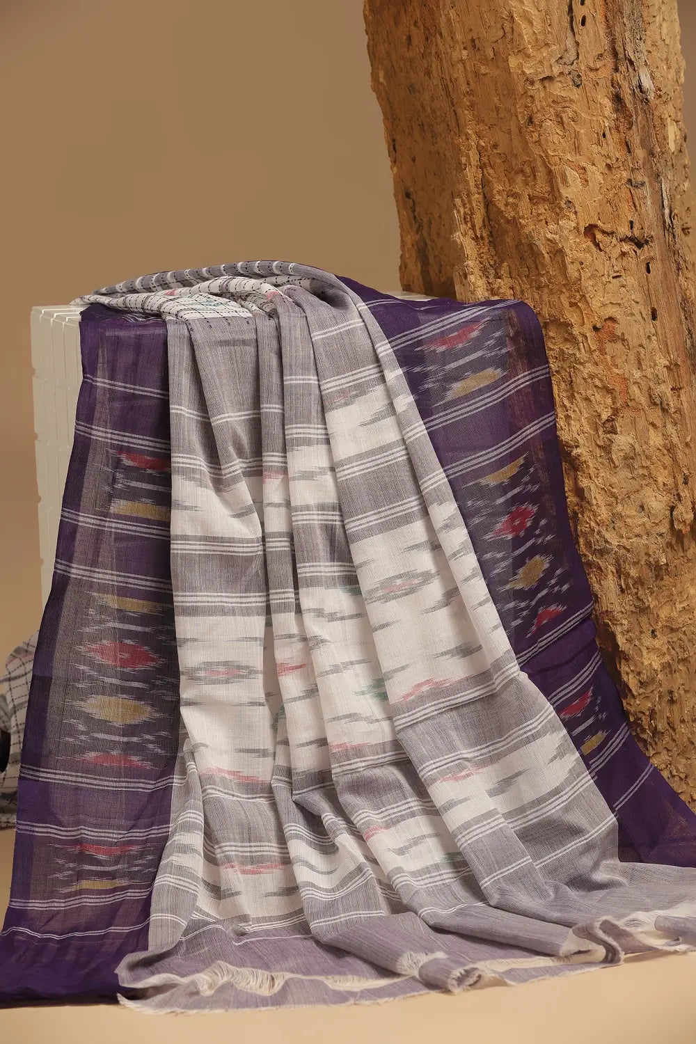 Folded view of the white Muthyampet check cotton saree resting against a rustic background