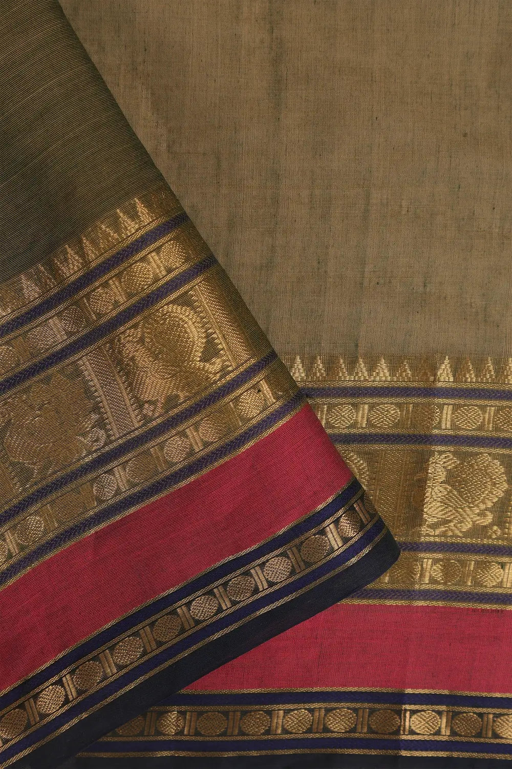 Close-up view of the rich gold zari border and contrasting edge framing the earth green cotton body