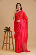 Full-length studio view of a model wearing the bright orange handwoven Chanderi pattu silk saree with a pink border and floral motifs, styled with traditional silver jewelry