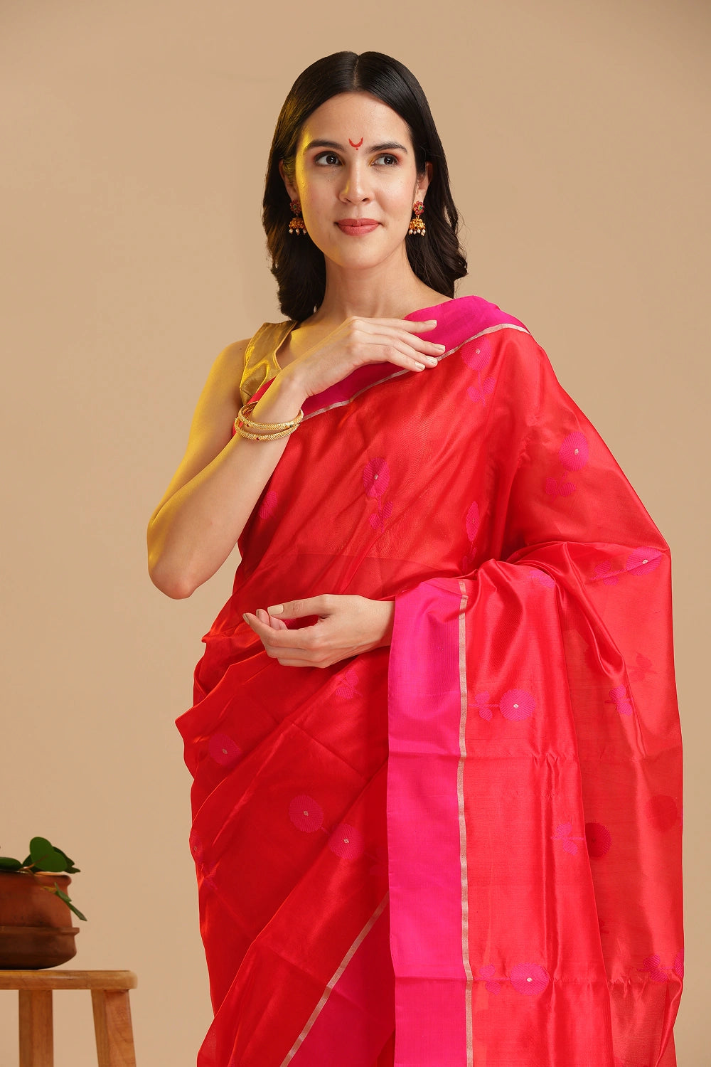 Studio standing angle view showcasing the graceful drape, vibrant orange body, and elegant pink border of the Chanderi pattu silk saree