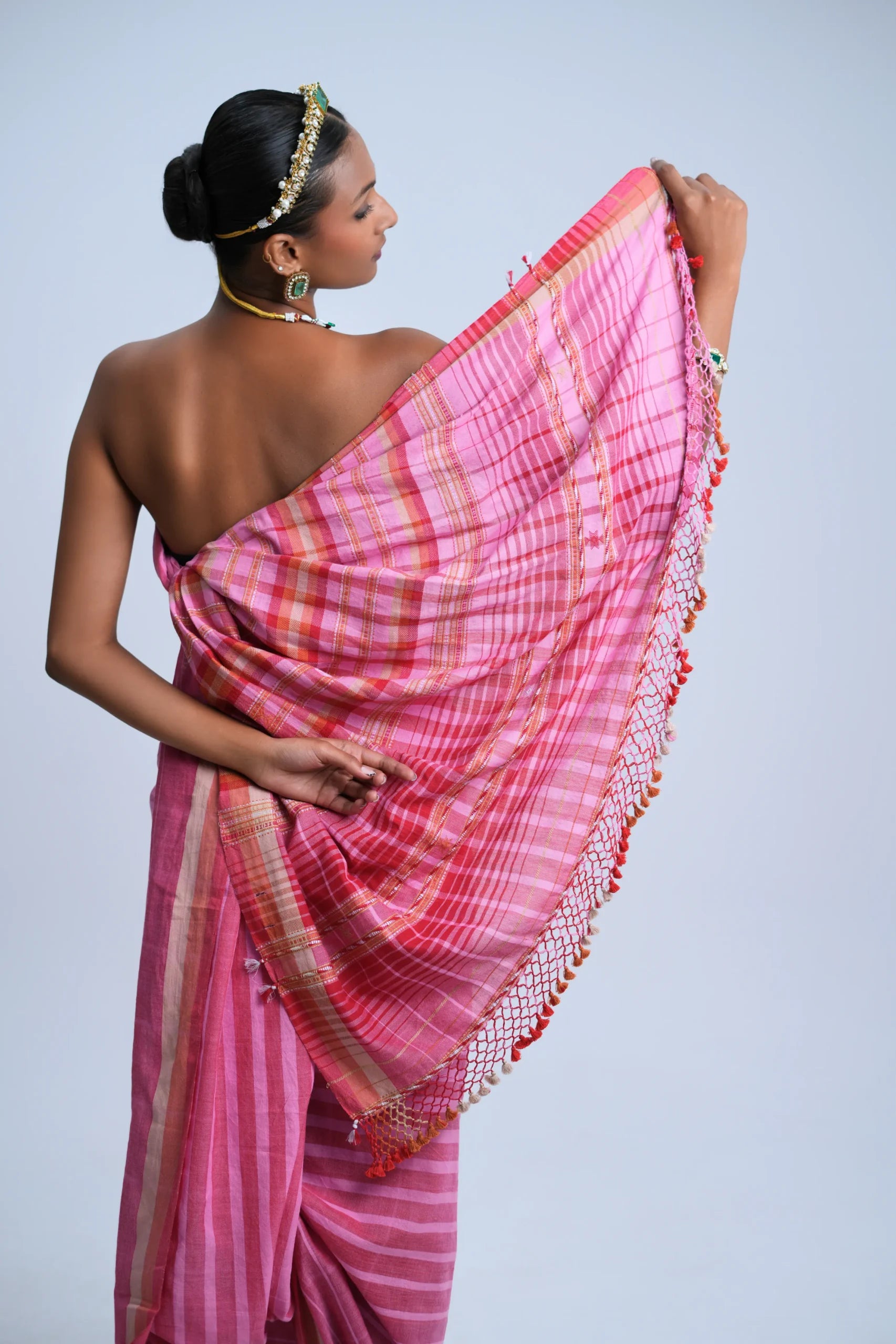 Close-up view of the densely woven check pallu and multicolour tassel fringe held over the model's arm