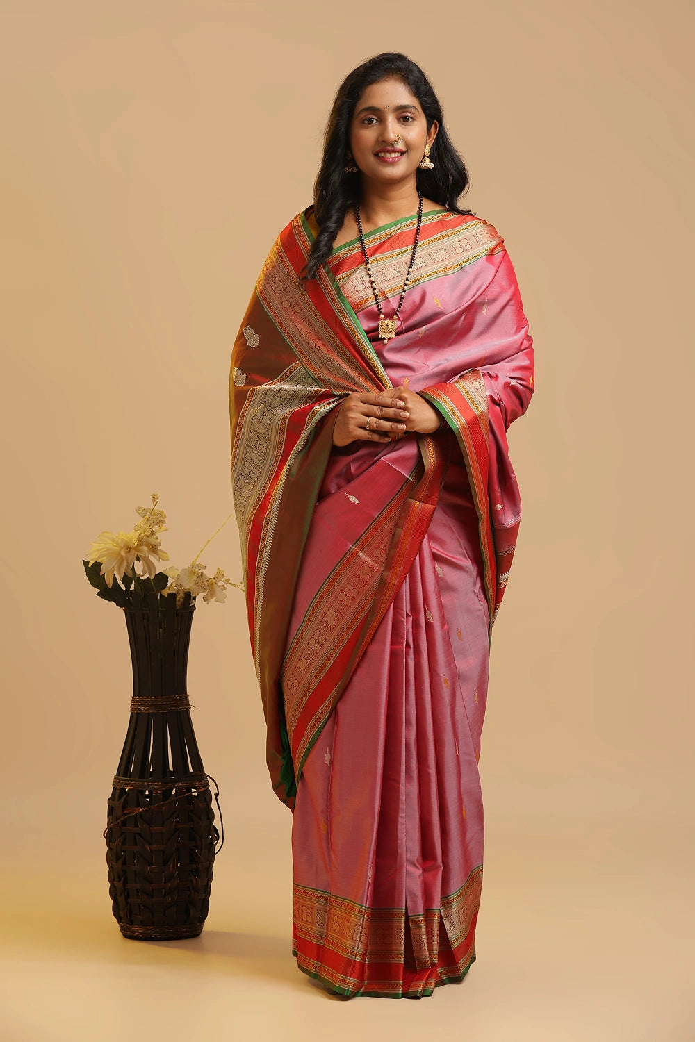 Model gracefully posing in the pink zero zari Kanchipuram silk saree against a neutral studio backdrop
