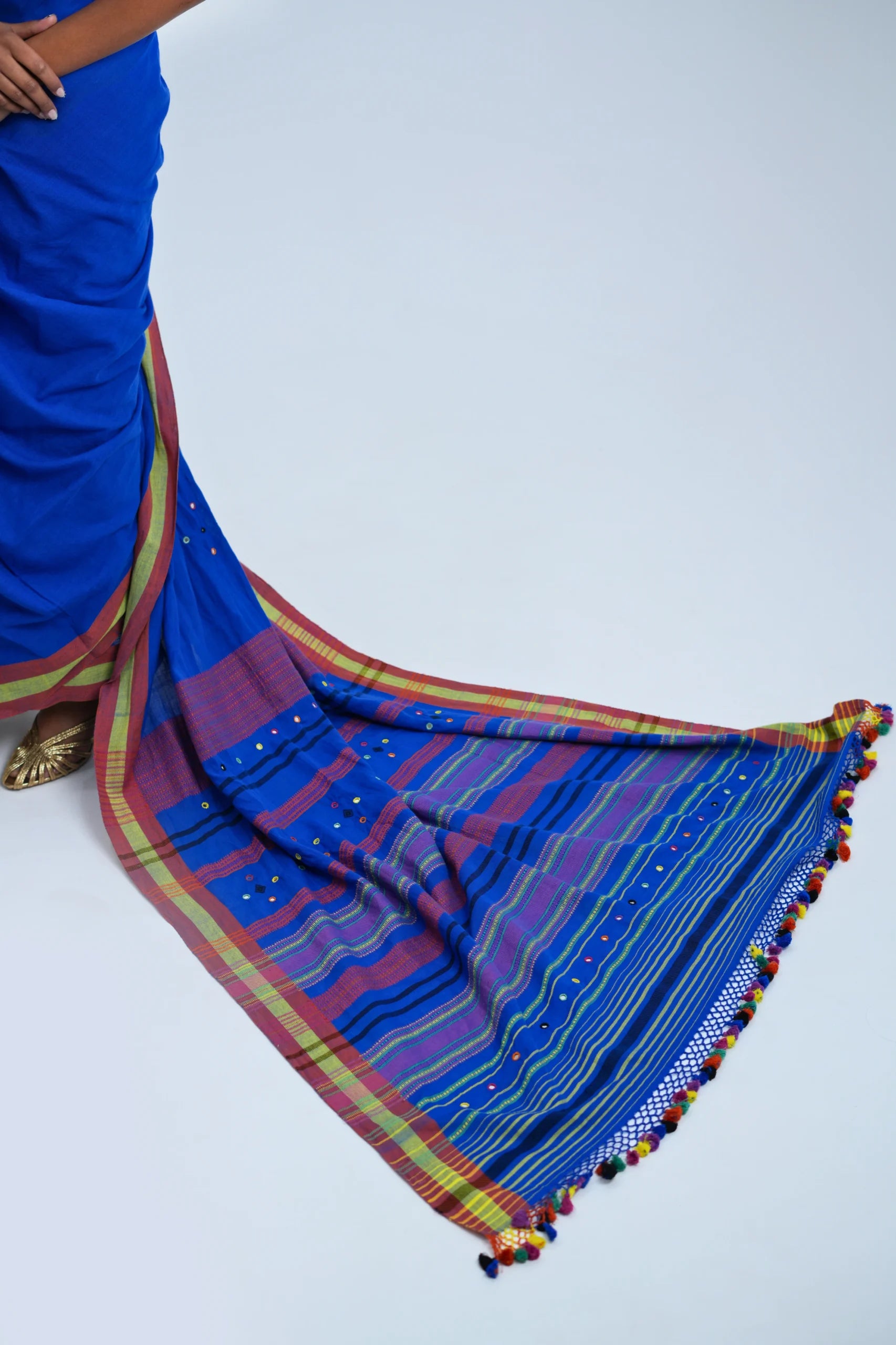 Detailed close-up of the richly layered horizontal stripe pallu, crochet-lace edge, and multicolour pom-pom tassel fringe
