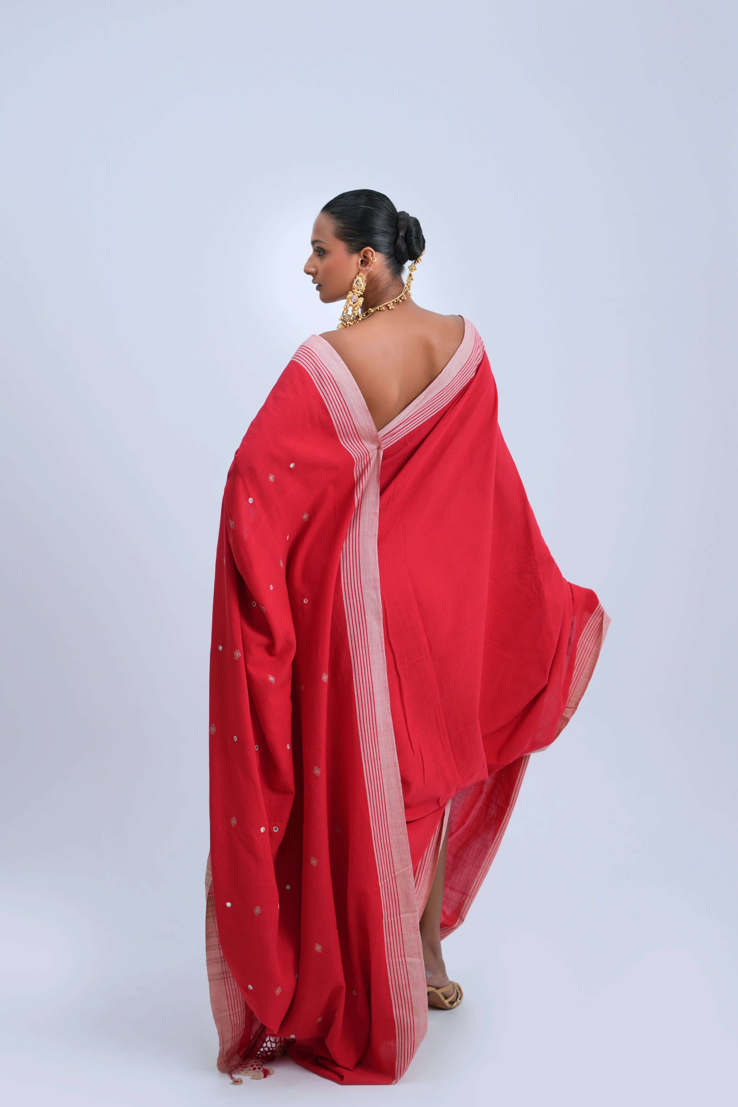 Rear full-length view of a model displaying the complete silhouette, vibrant red fabric, and elegant border alignment